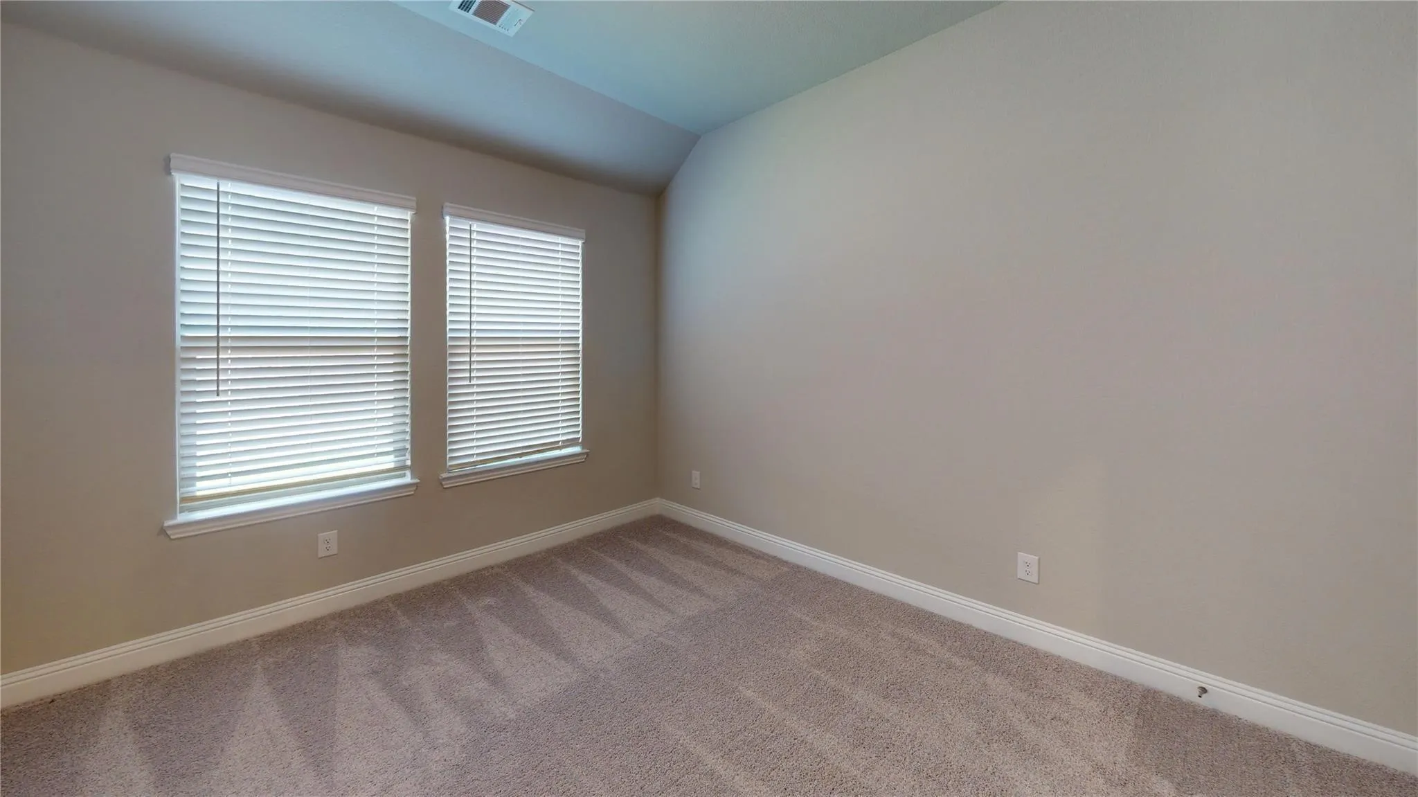 Neutral tone carpeting with light-colored walls and two windows
