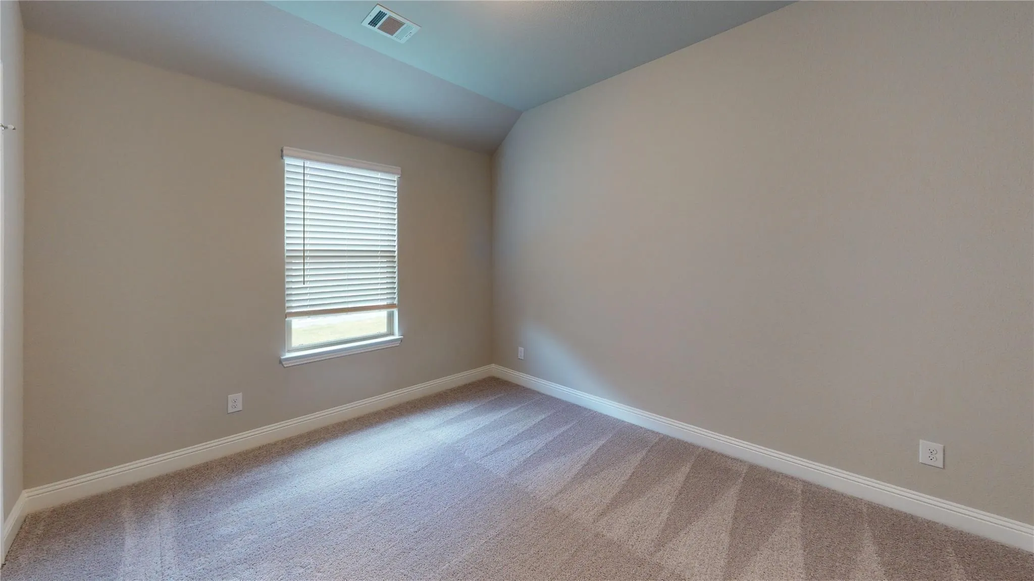 Neutral paint palette, window with blinds, vaulted ceiling, and patterned carpeting