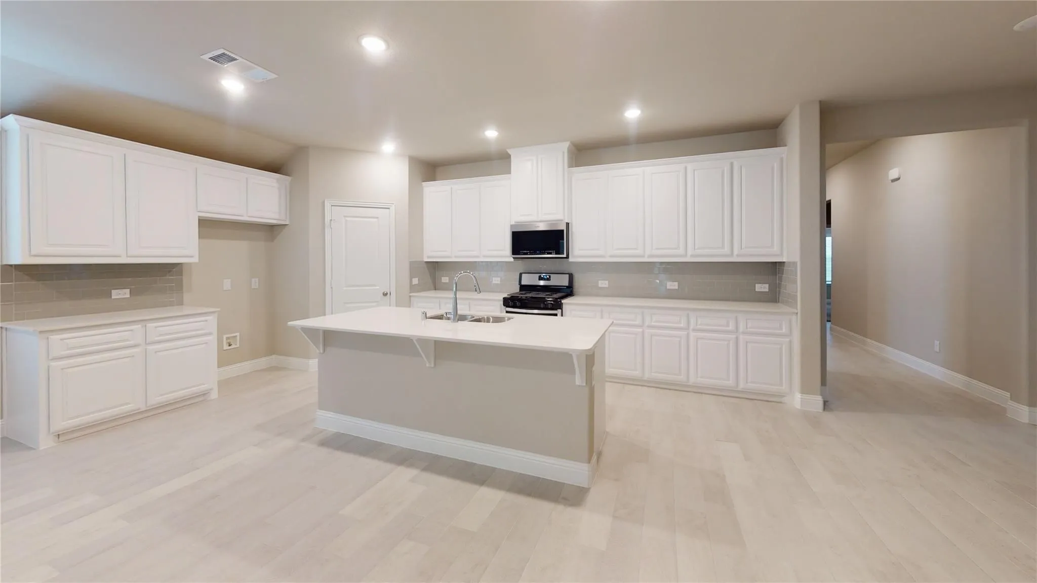 Spacious kitchen featuring white cabinetry, light-toned flooring, a center island with a sink, stainless steel appliances, and recessed lighting
