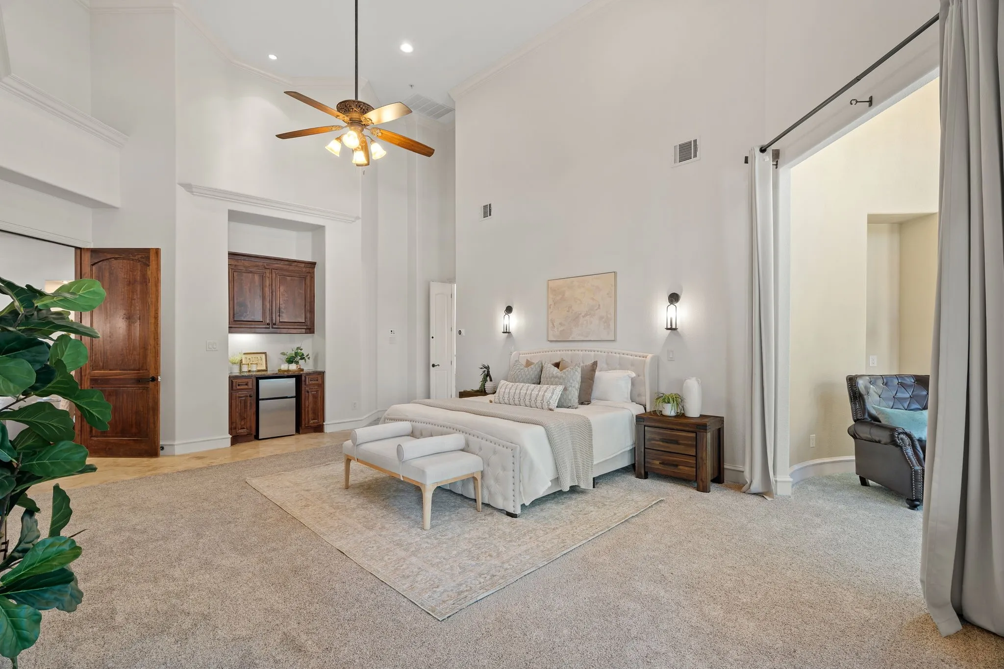 Vaulted ceilings with recessed lighting, ceiling fan, and wall sconces, sitting area, wet bar and exterior access to patio