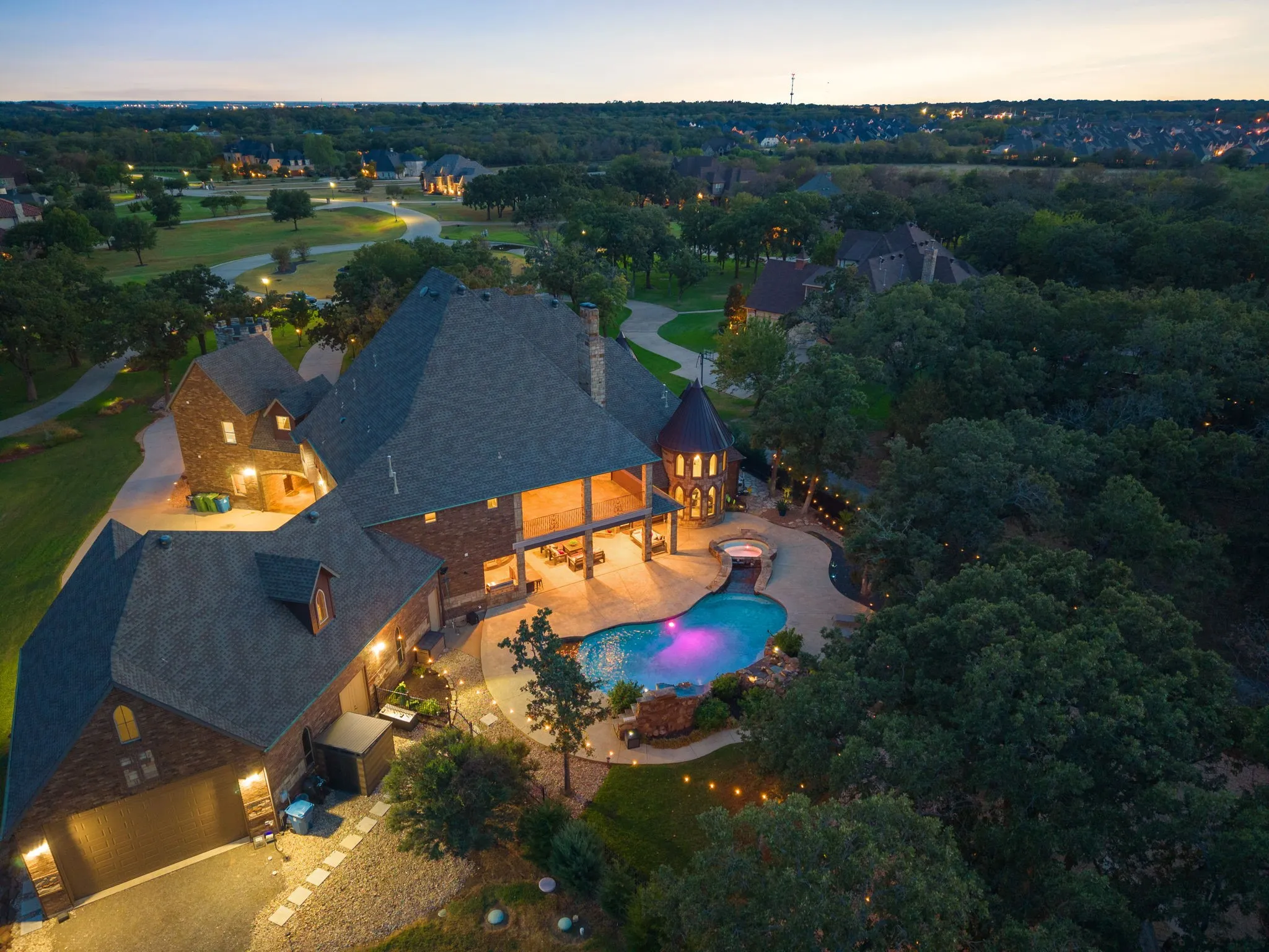 Brick exterior with multiple gables, extensive paved patio, built-in swimming pool, integrated spa, and an attached garage