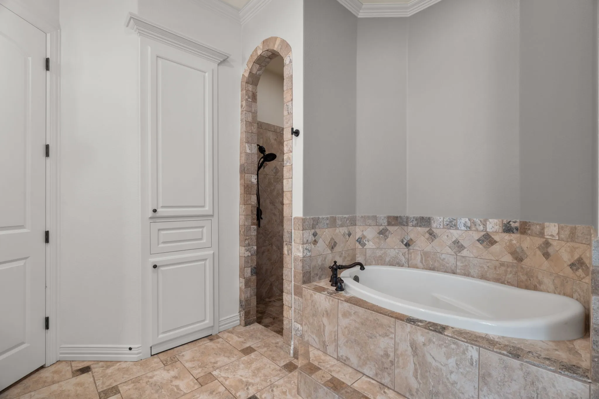 Built-in soaking tub with decorative tile surround and oil-rubbed bronze fixtures, walk in tile shower and 2nd closet