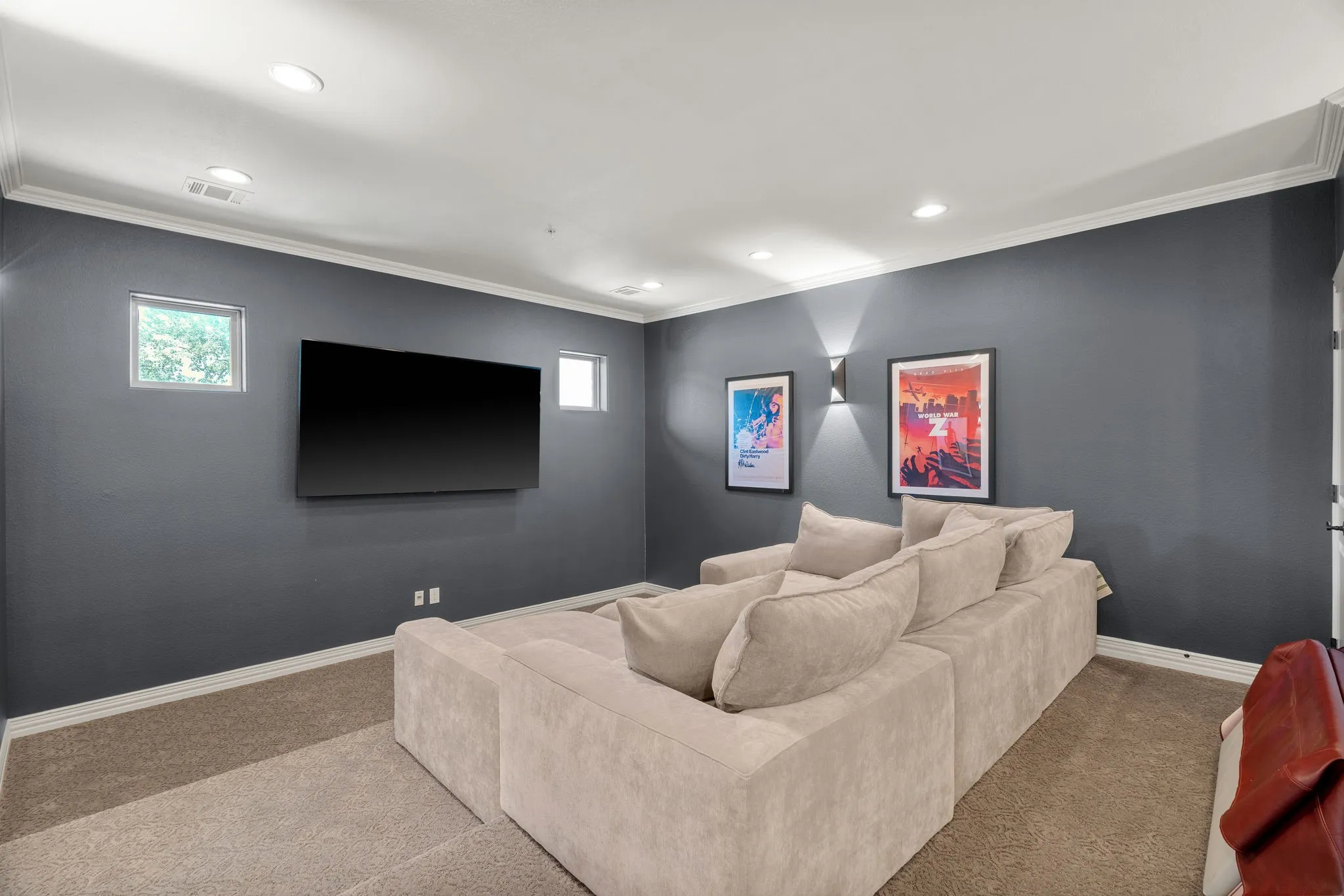 Recessed ceiling lighting, wall-mounted television, crown molding, two small windows, and sconce lighting, tiered seating and a granite bar for additional seating