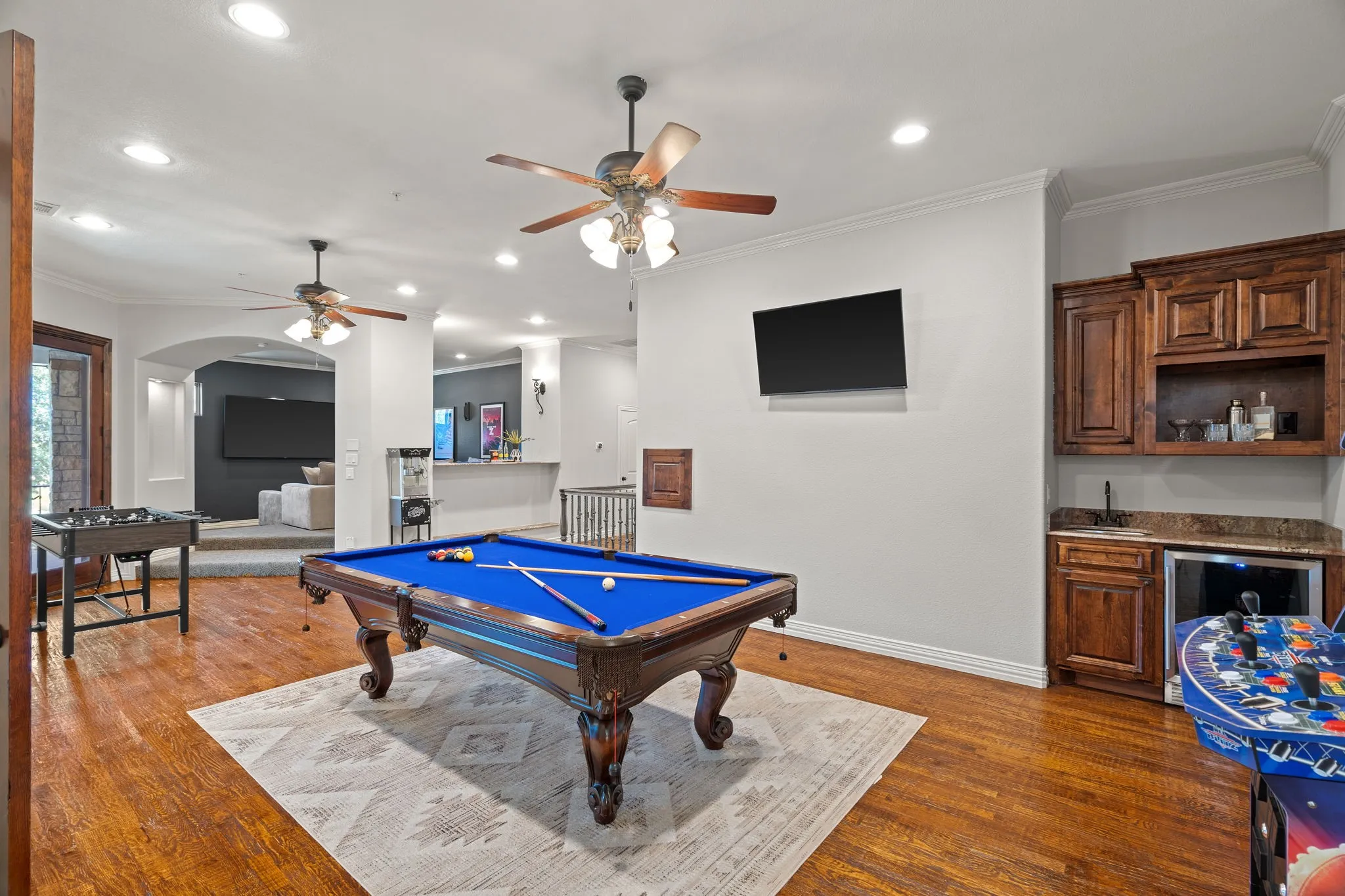 Hardwood flooring, recessed lighting, crown molding, built-in wet bar with cabinetry, and ceiling fans and laundry chute, and balcony overlooking great room