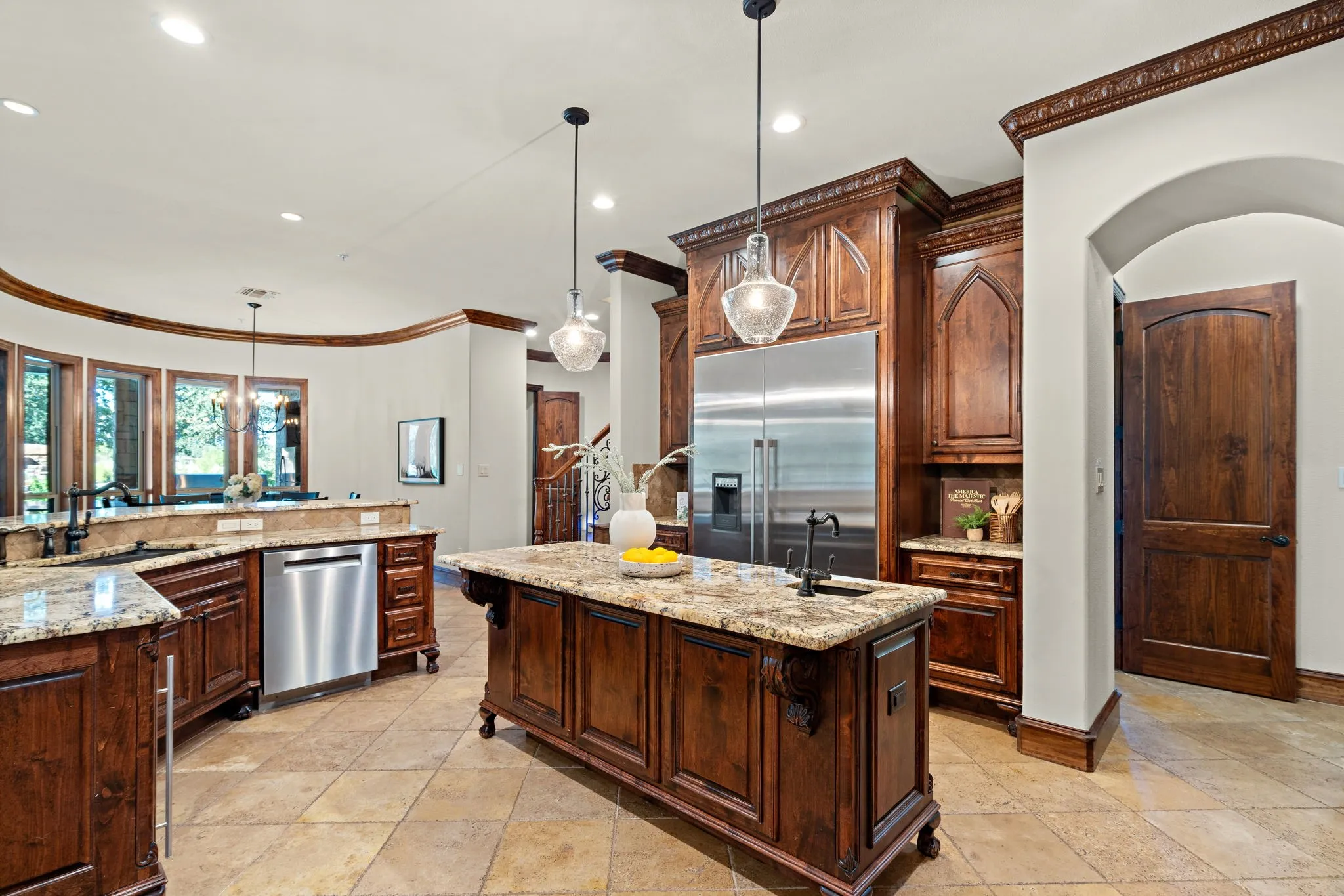 Gourmet chef's kitchen with rich wood cabinetry, stainless steel appliances, granite countertops, and tile flooring, pot filler, prep sink and double ovens