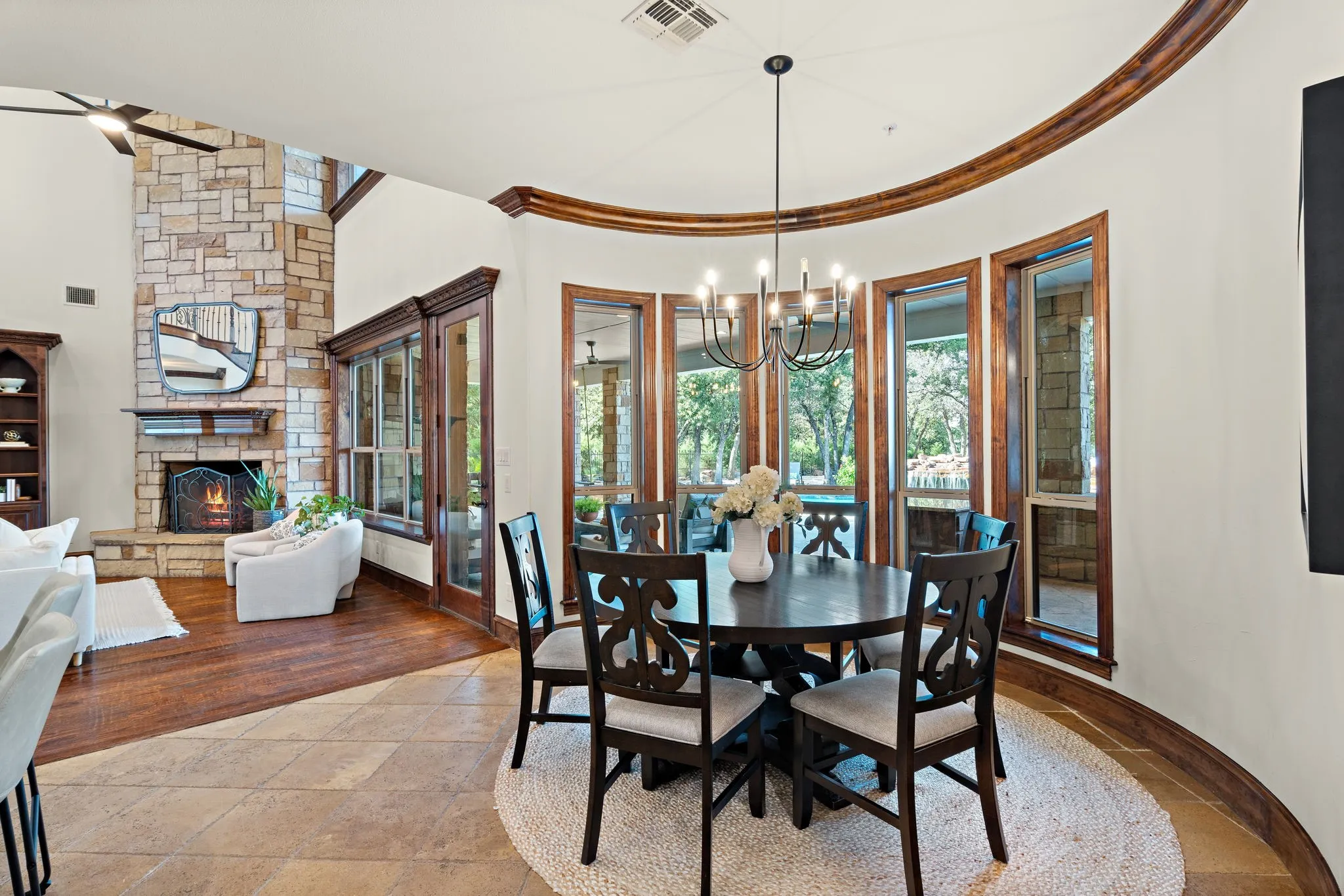 Curved dining area with wood-framed windows, tile flooring, and a chandelier