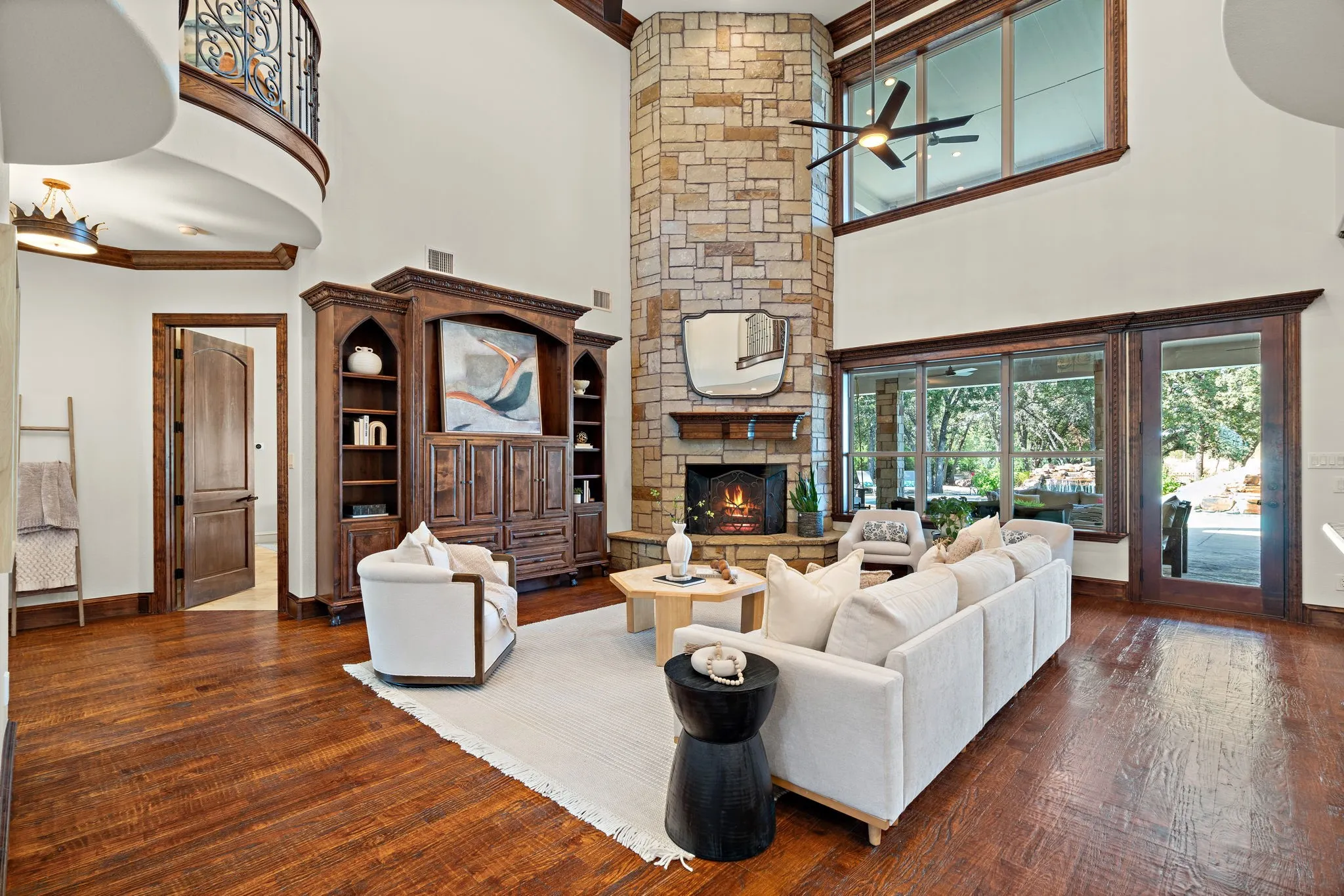 Vaulted ceilings with an exposed wood beam, a floor-to-ceiling stacked stone fireplace, wood-finish flooring, and a built-in entertainment center with integrated shelving