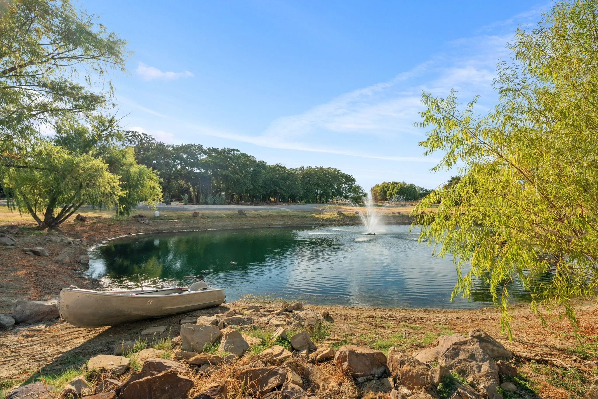 Stocked fishing pond with fountain, surrounded by mature trees and natural landscaping