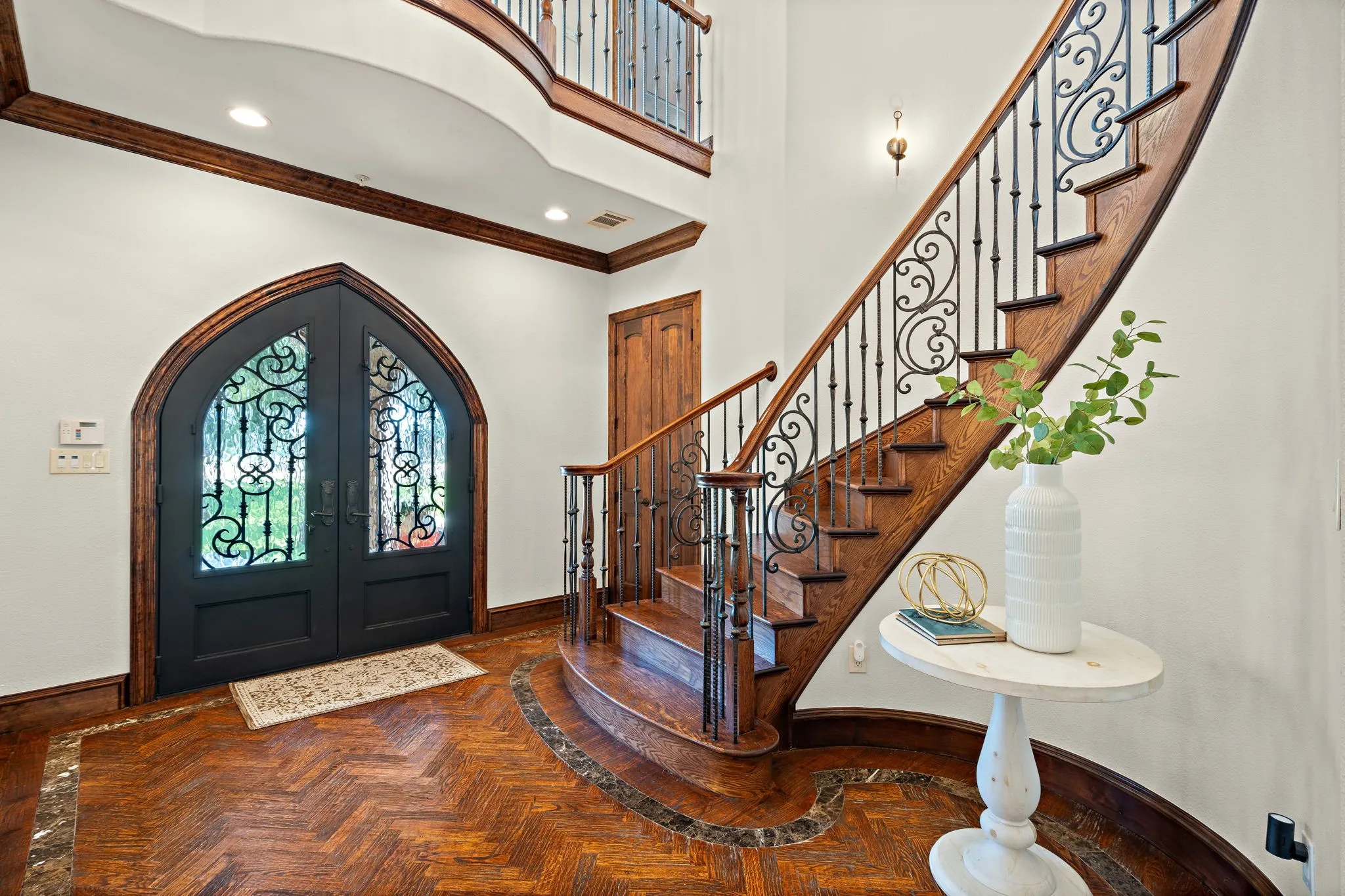 Arched double entry doors with decorative glass inserts and spiral staircase