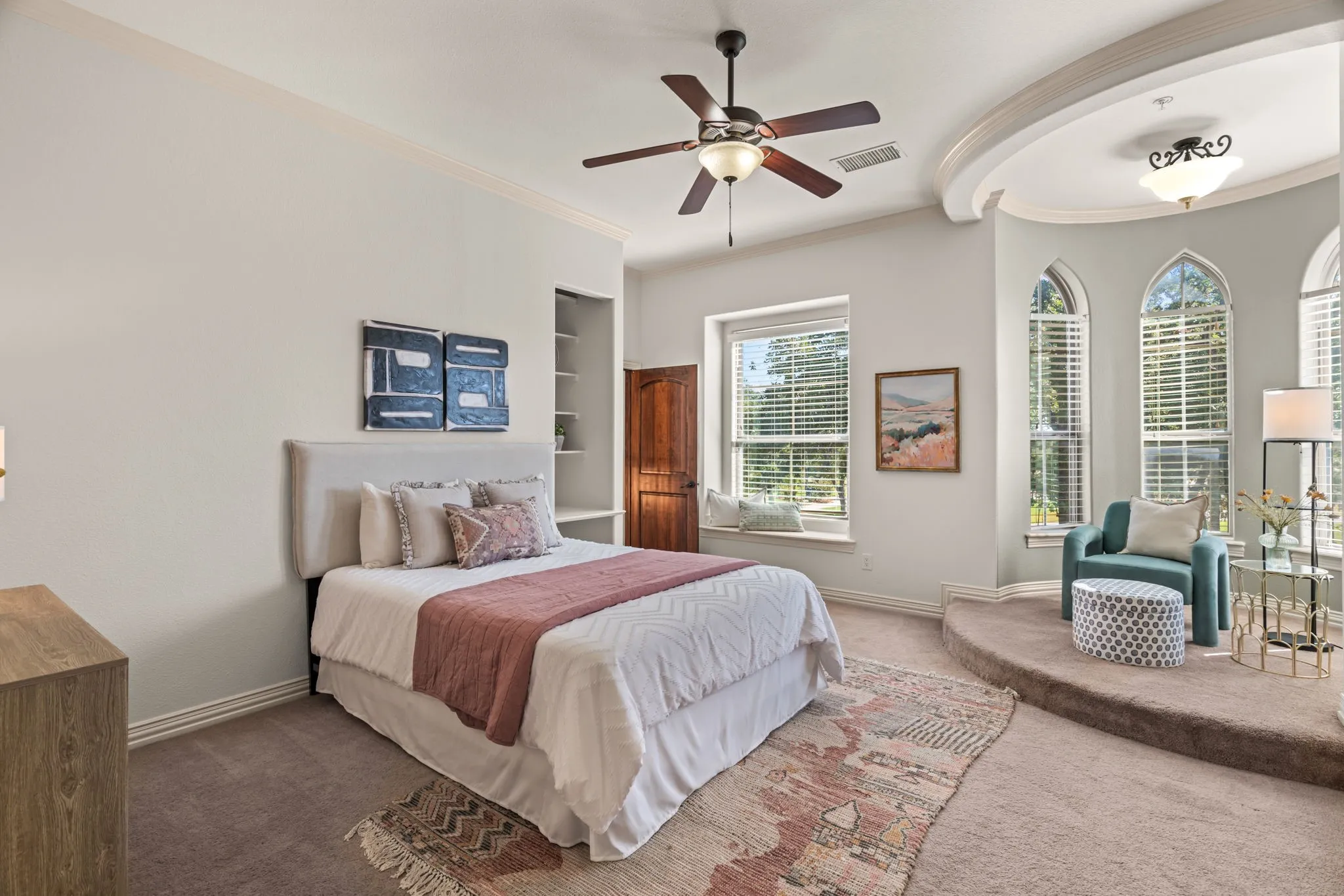 2nd floor bedroom with recessed ceiling feature, arched windows, built-in shelving, ceiling fan light fixture, and window seat. This room has a closet in the bedroom and another closet in the en-suite bathroom