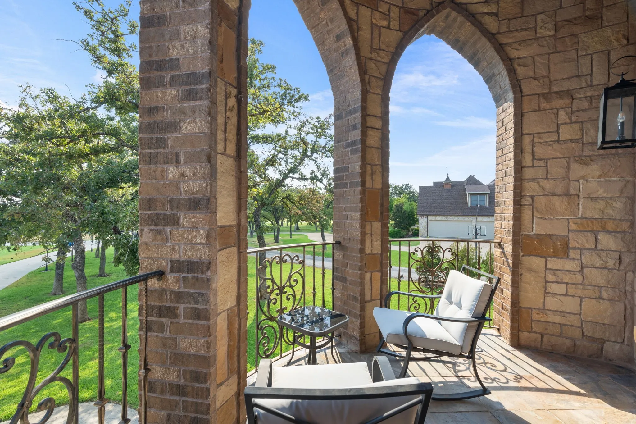Stone and brick archway balcony featuring a metal railing and an attached exterior light fixture