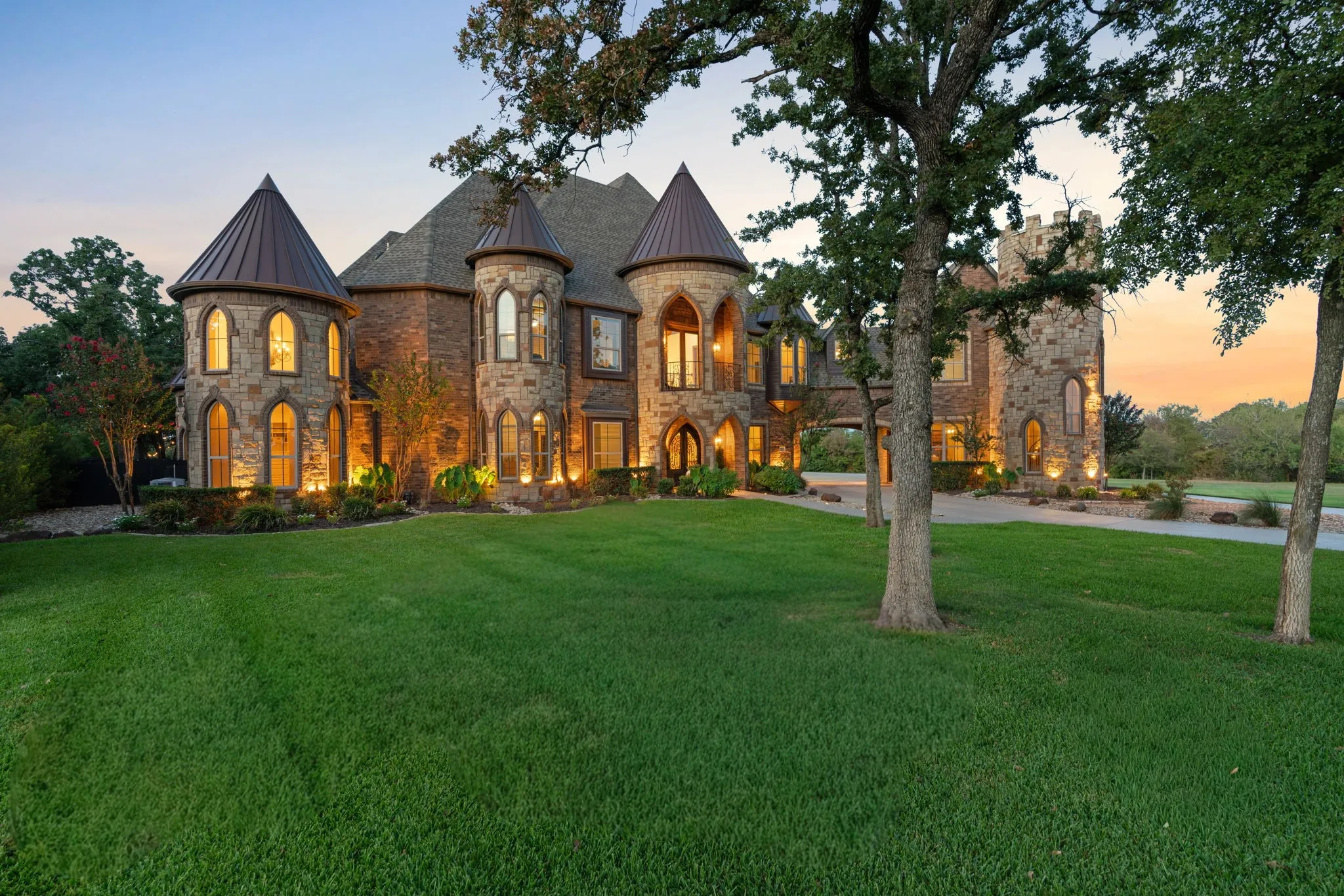 Stone exterior residence featuring multiple turrets with conical roofs, arched windows, and a paved drive