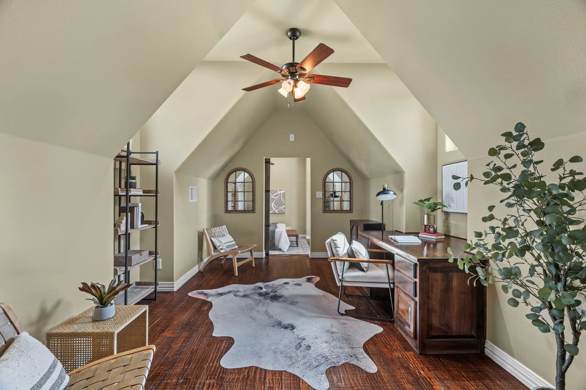 Secondary living space accessible from upstairs with  vaulted ceilings, wood-finish flooring, ceiling fan with light fixture, and arched windows