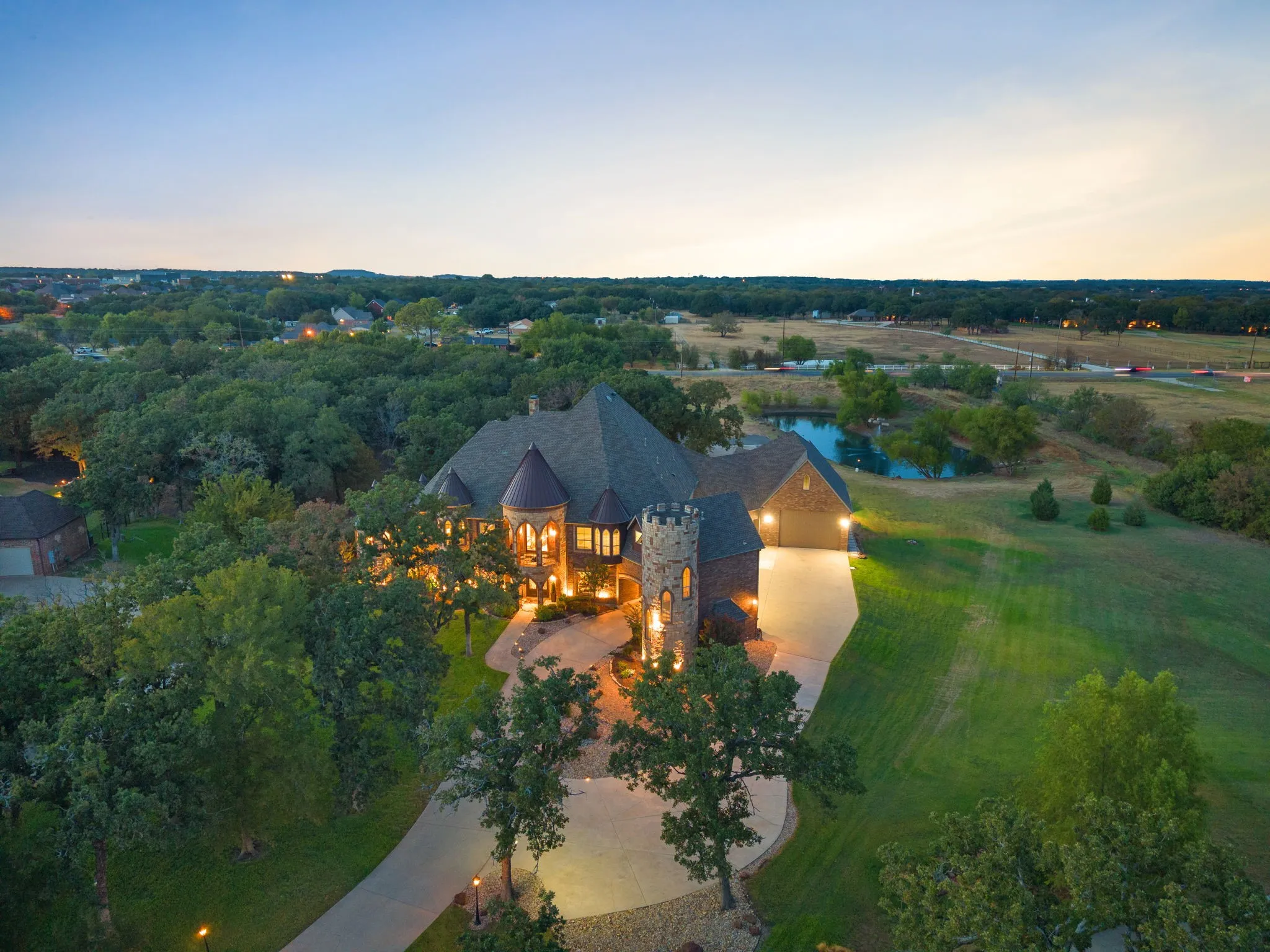 Custom stone-clad residence featuring a turret and multiple gables, circular driveway and porte-cochere