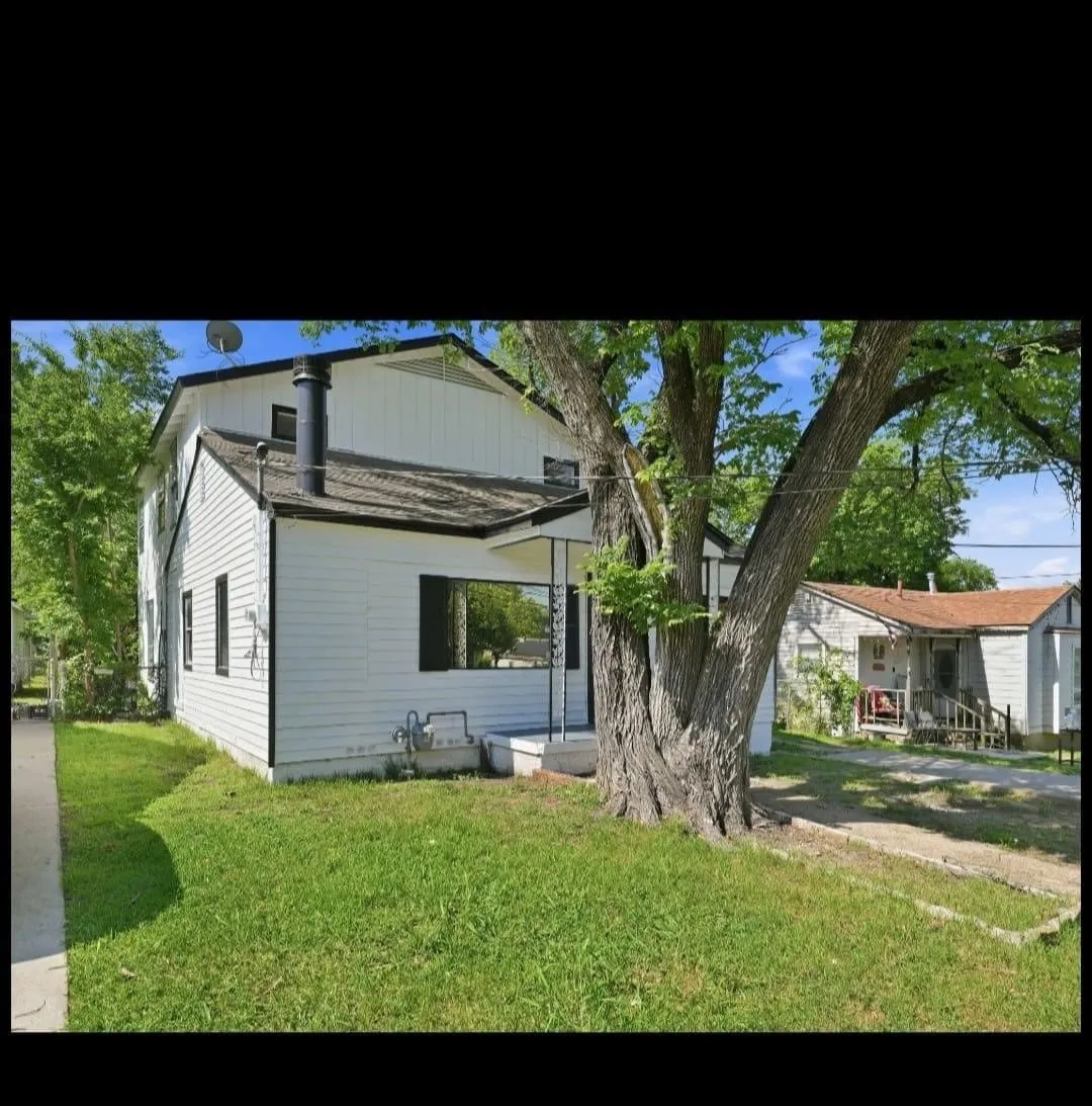 White exterior siding, dark roof, prominent chimney, mature tree, concrete pathway