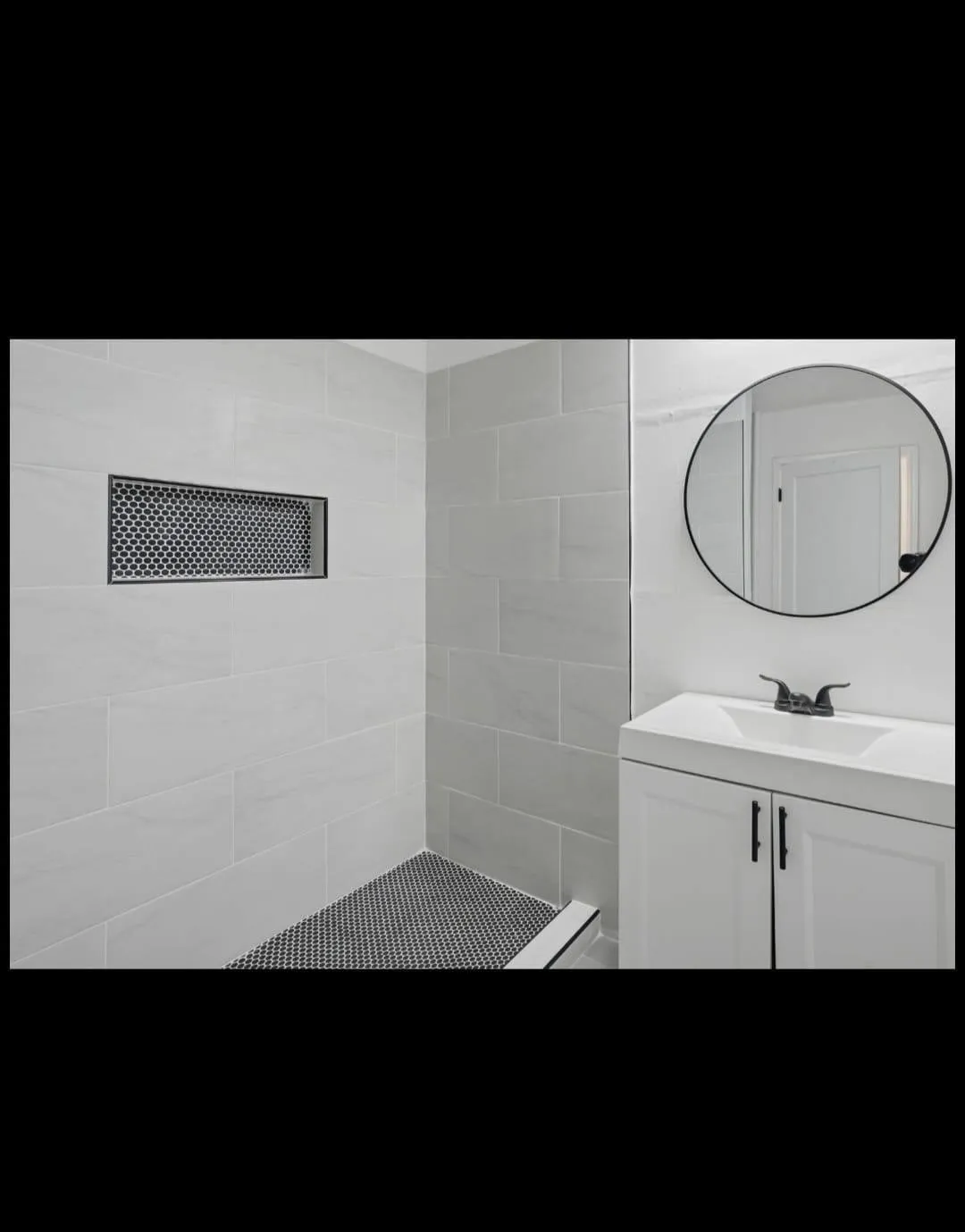 White tiled shower with a black honeycomb tile floor