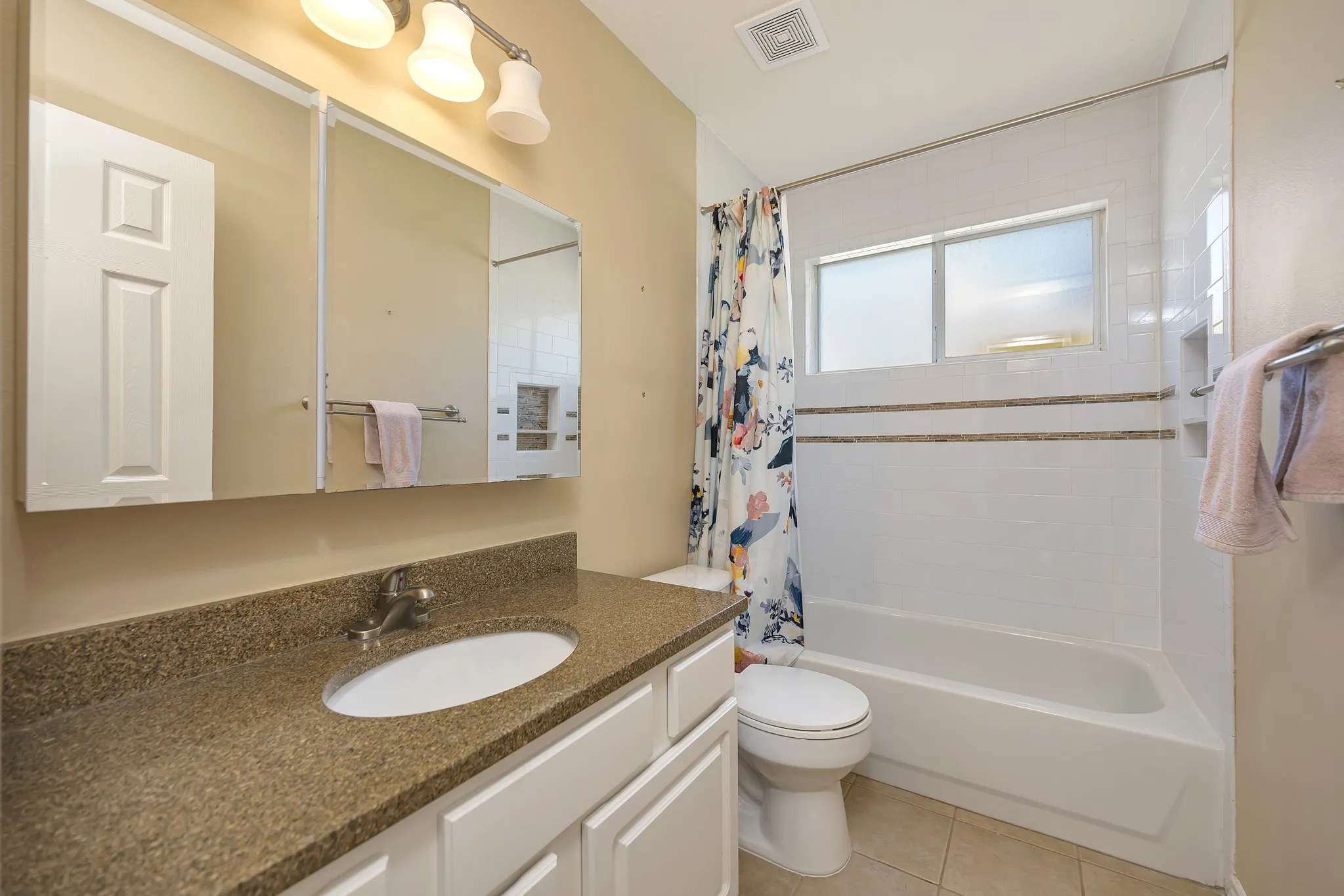 White vanity with a neutral-toned countertop, oval undermount sink, and chrome faucet