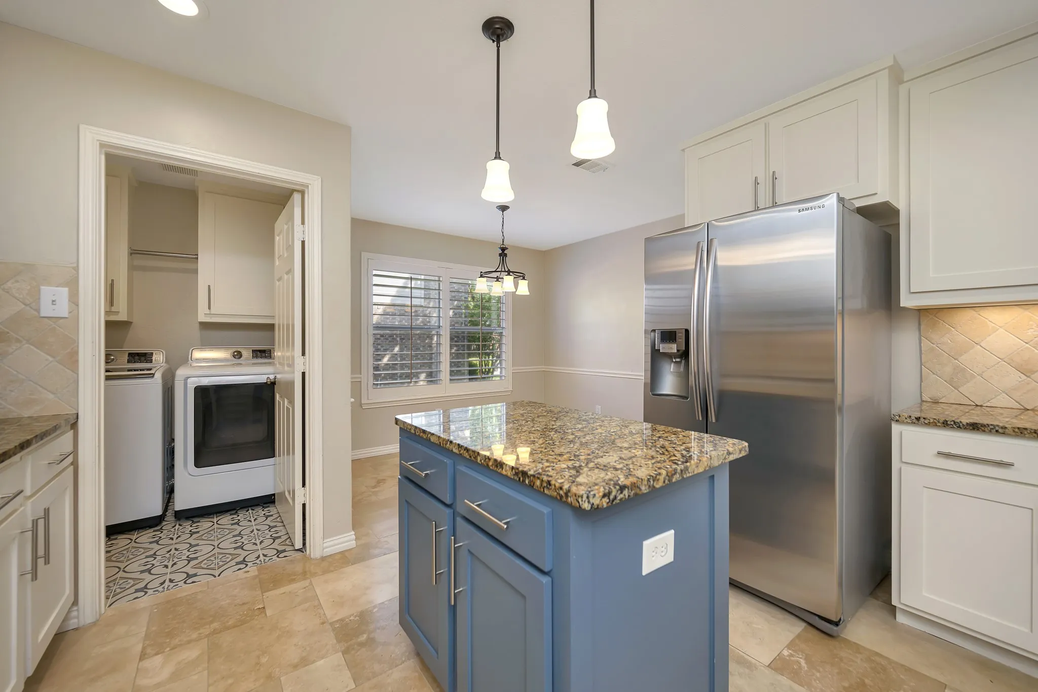 Kitchen featuring a blue island with a stone countertop, white cabinetry with under-cabinet lighting, and stainless steel appliances