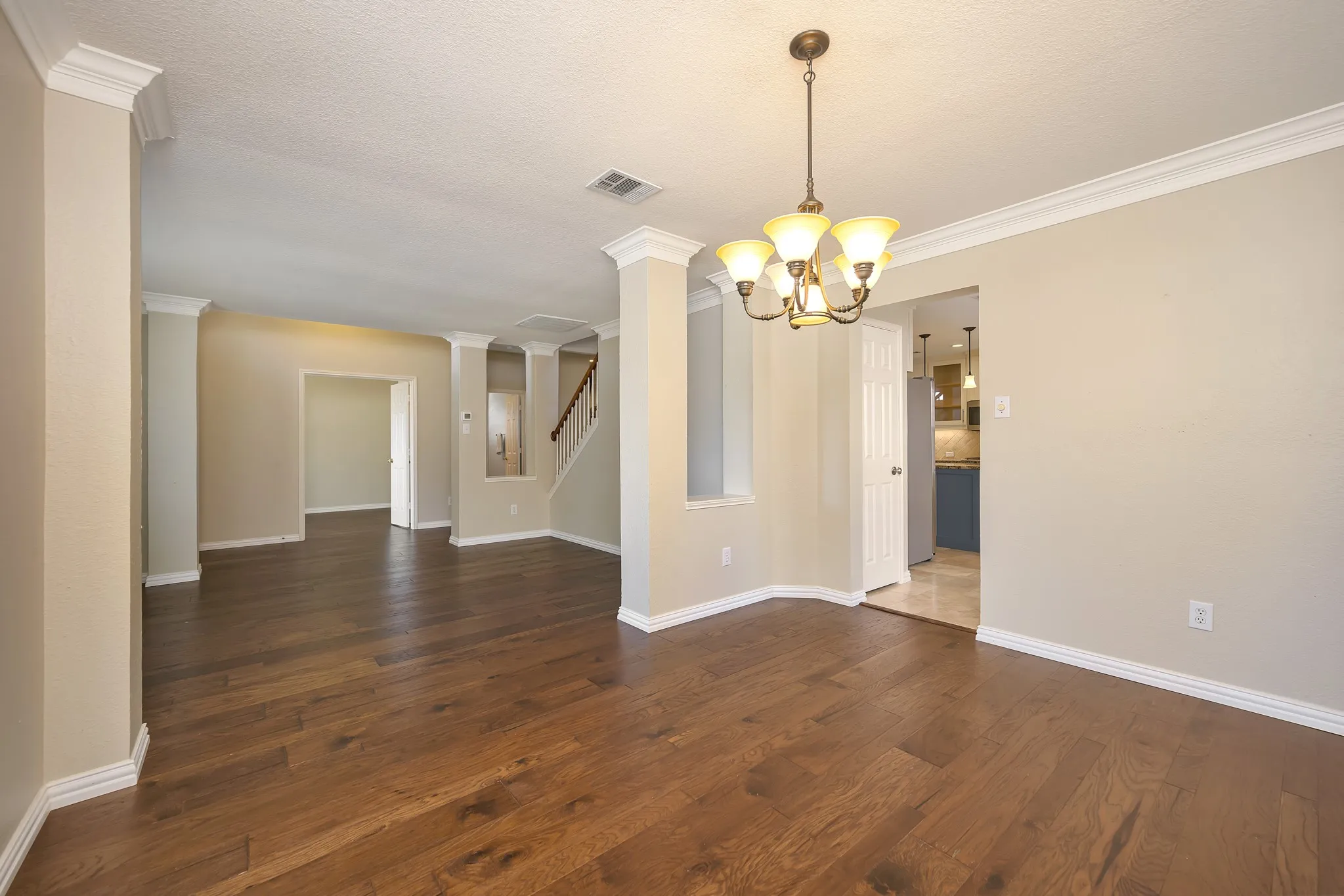 Wood-finish flooring, crown molding, and a decorative chandelier