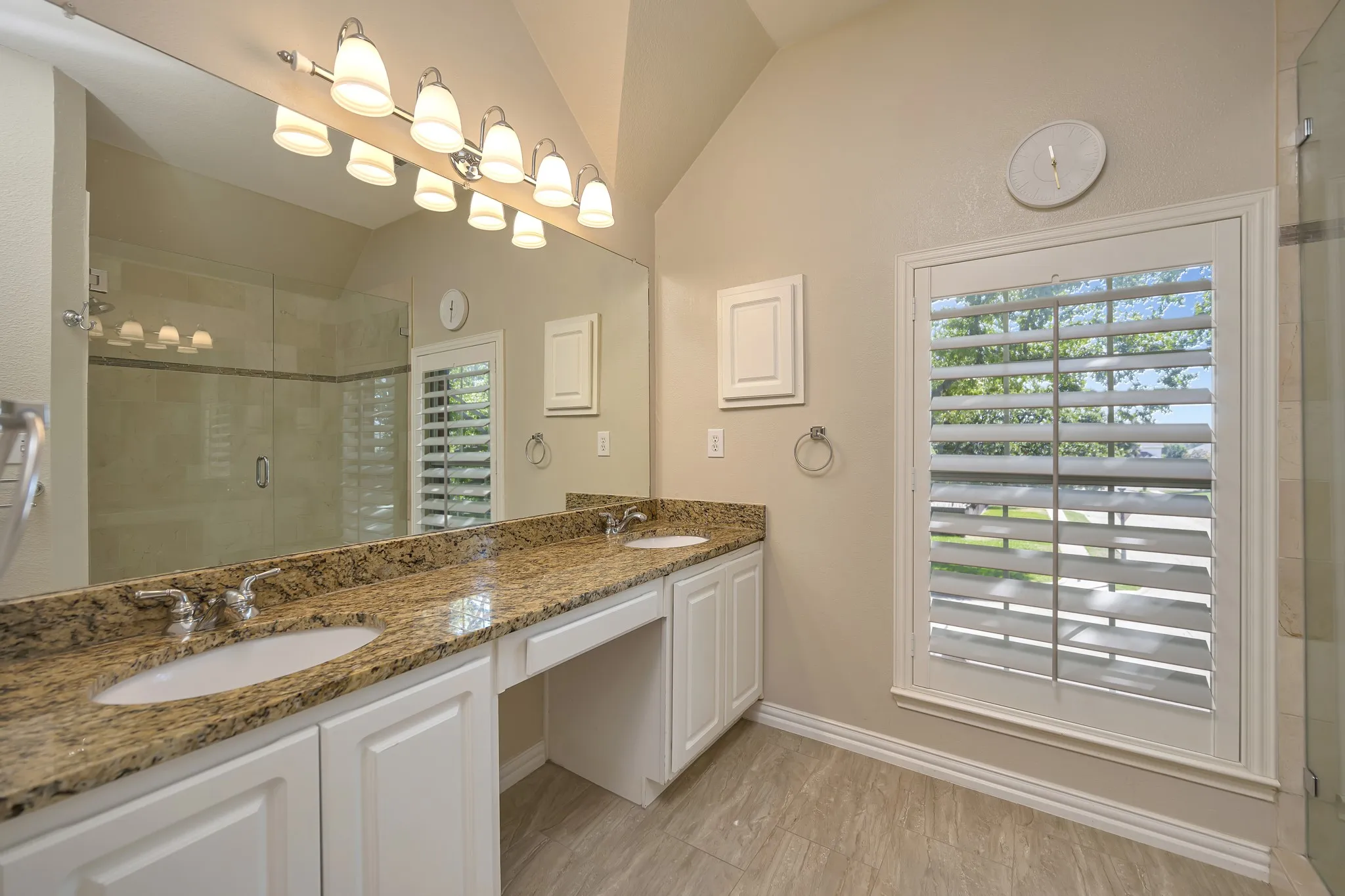 Double vanity with undermount sinks, granite countertops, and white cabinetry