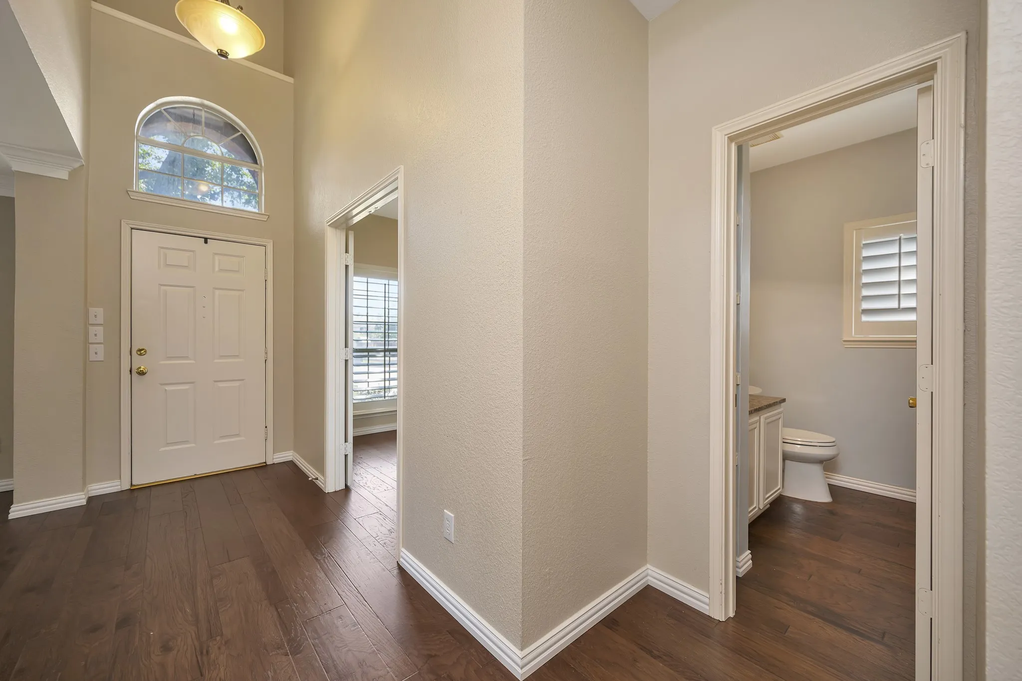 Entryway with high ceilings, wood-finish flooring, and an arched transom window above the front door
