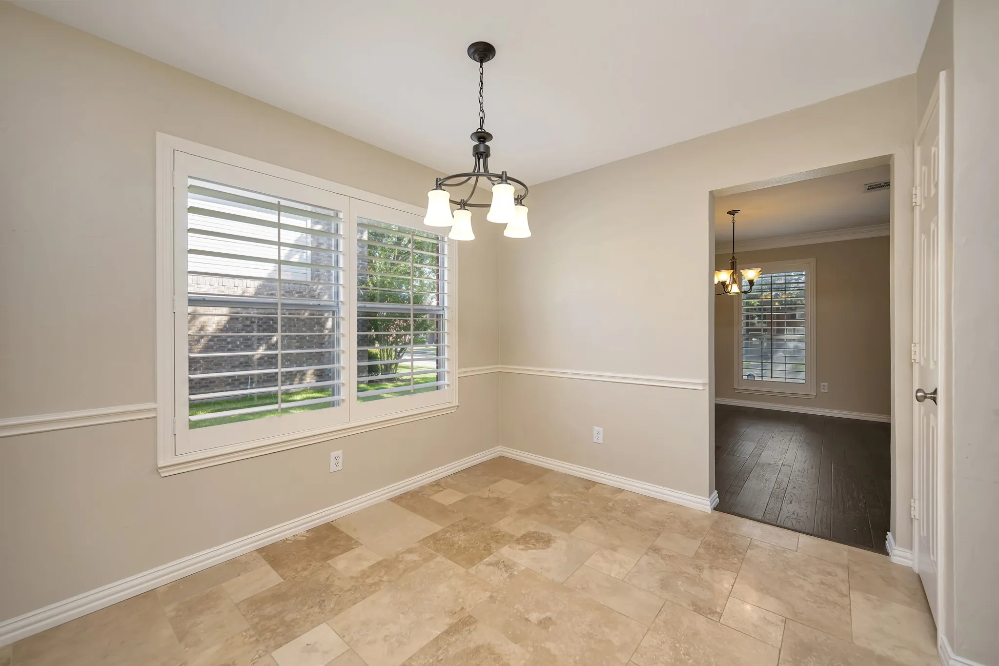 Recessed lighting, crown molding, chair rail molding, tile flooring, and a decorative chandelier