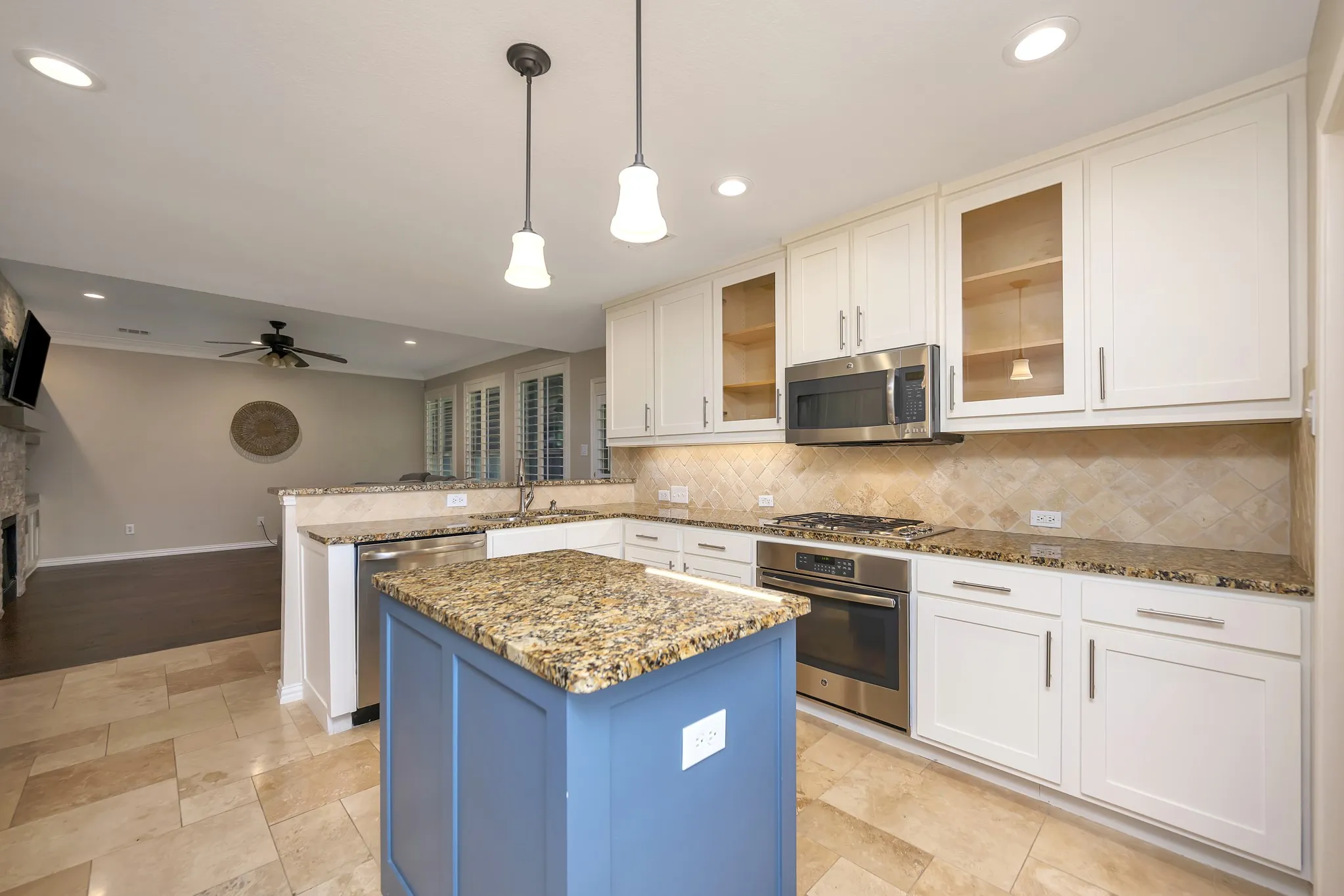 Kitchen featuring an island with a stone countertop, white shaker cabinetry, stainless steel appliances, a tile backsplash, and recessed lighting