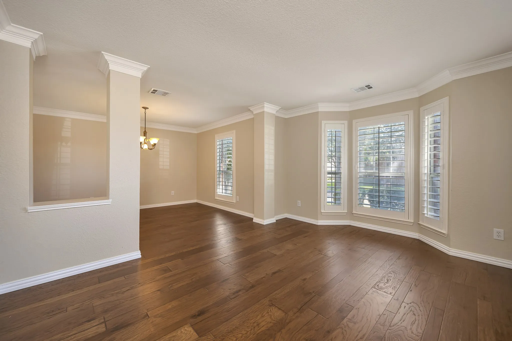 Hardwood flooring, bay windows, crown molding, plantation shutters, and a pass-through opening