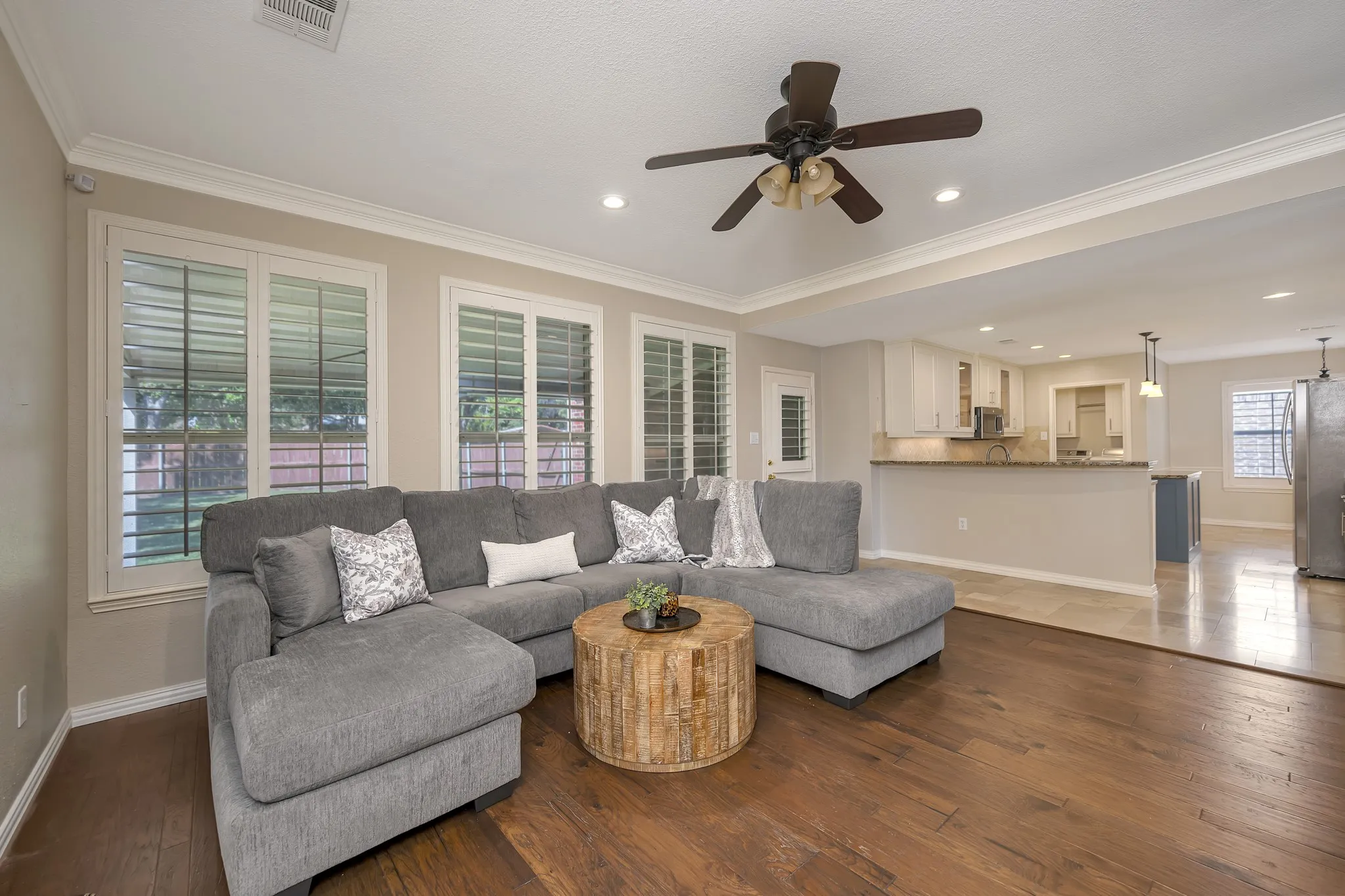 Hardwood-style flooring throughout, white crown molding, recessed lighting, and a ceiling fan