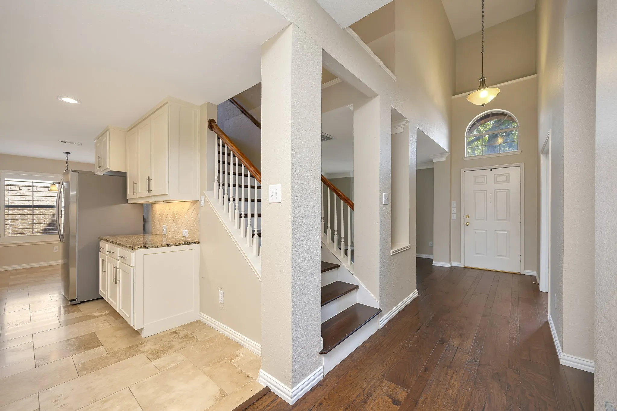 Two-story foyer with a vaulted ceiling, wood-finish flooring, and an arched transom window