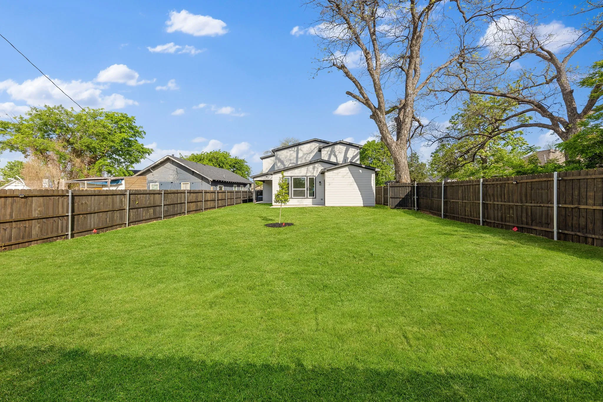 Expansive fenced backyard with a well-maintained lawn and mature trees