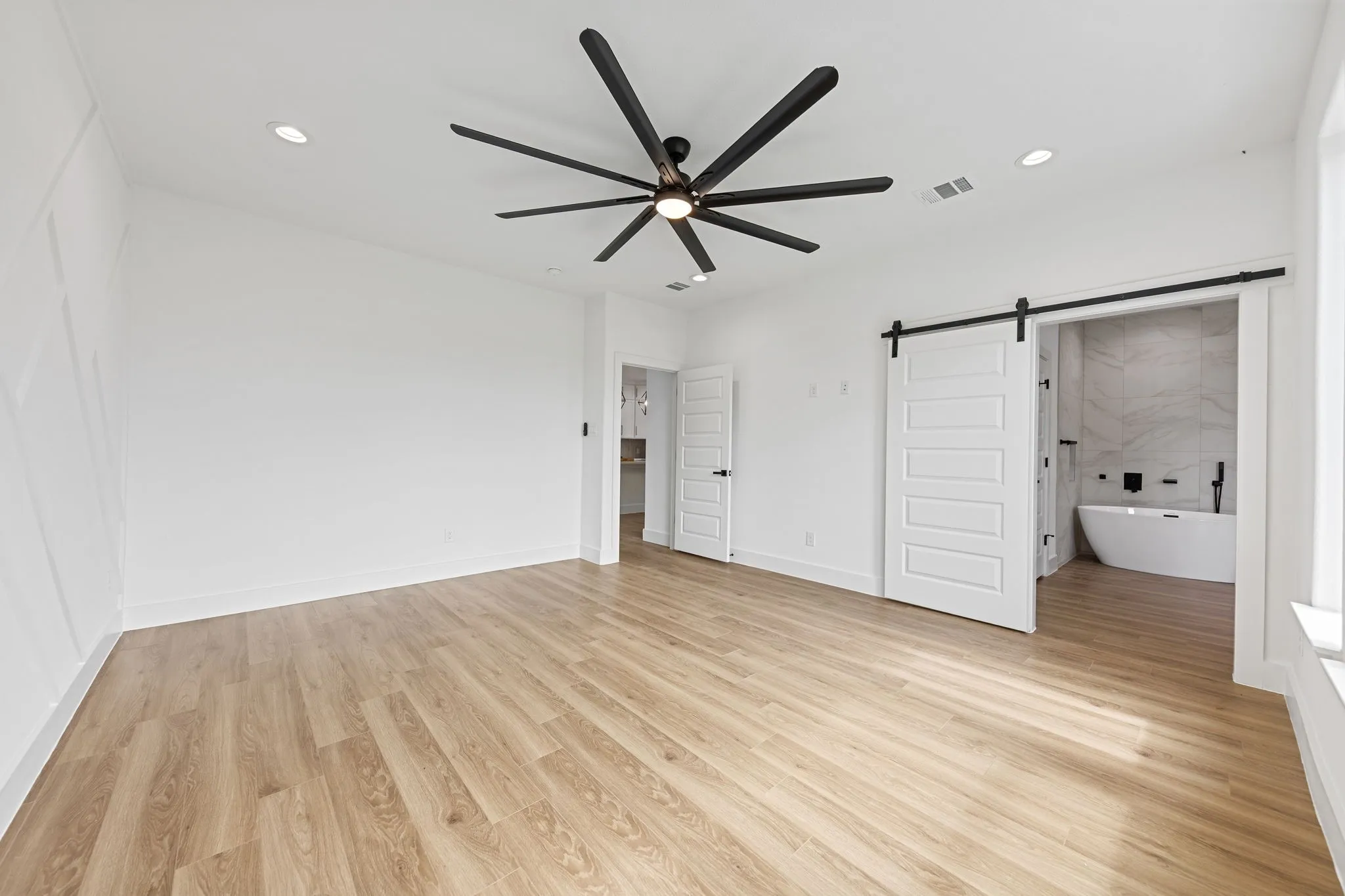 Spacious room featuring wood-finish flooring, recessed lighting, and a modern ceiling fan