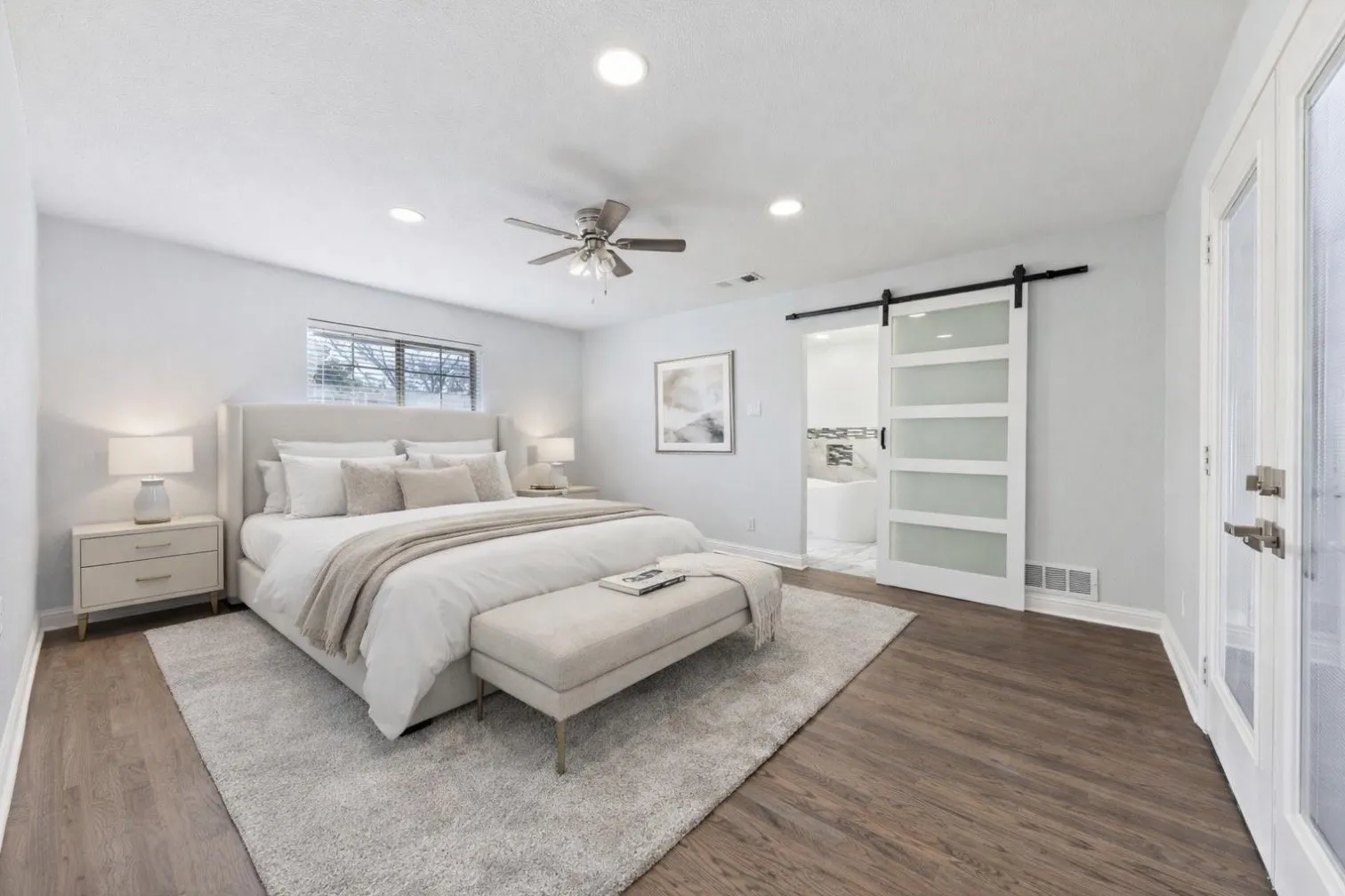 Wood-finish flooring with a ceiling fan, recessed lighting, and a barn door with frosted glass panels