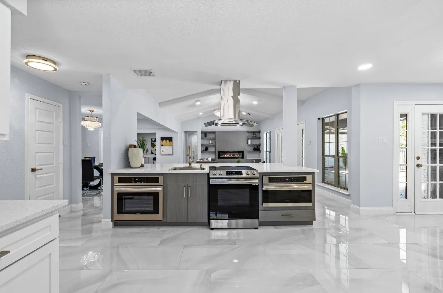 Spacious kitchen island with integrated stainless steel appliances, modern gray cabinetry, and light-toned countertops