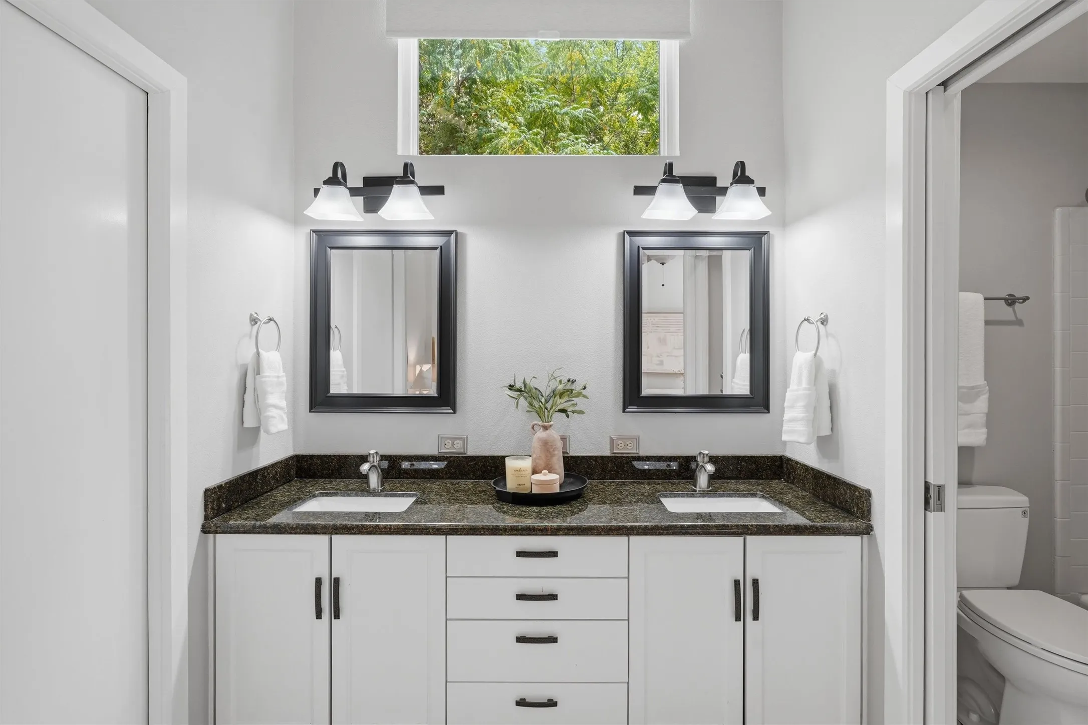 Primary vanity area with dual sinks, and transom window that lets in natural light.