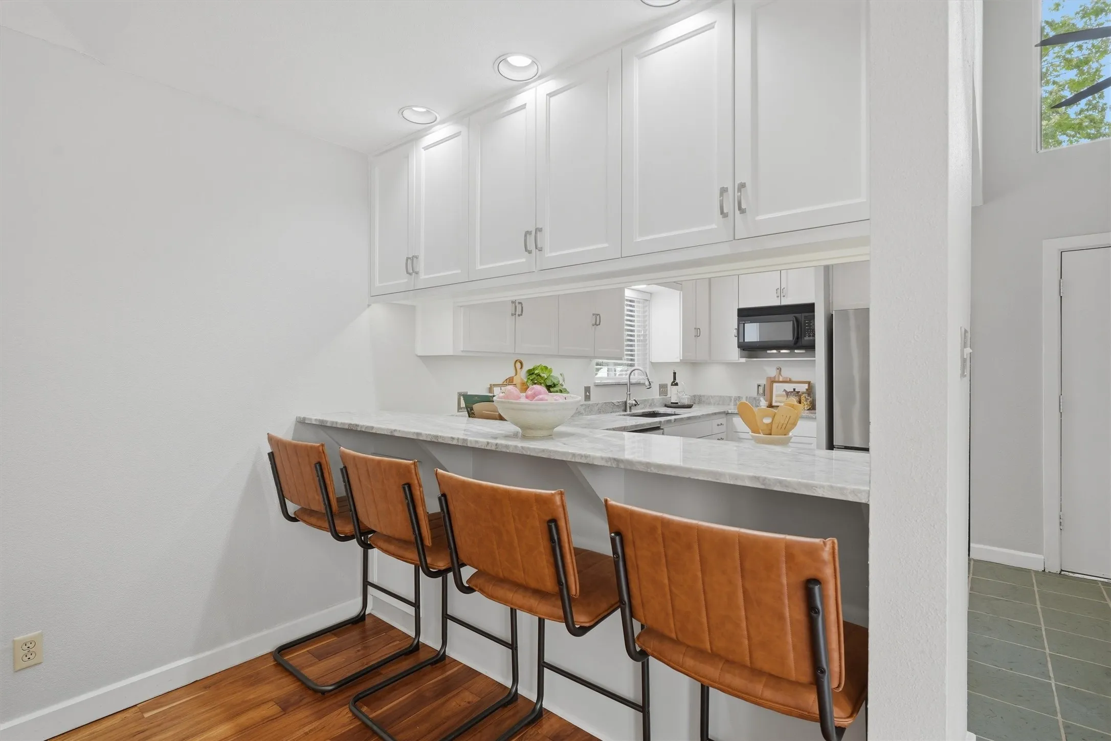 Designed for effortless casual dining, this spacious breakfast bar features premium stone countertops, recessed lighting, and built-in upper cabinetry that optimizes storage while keeping the space open to the living room