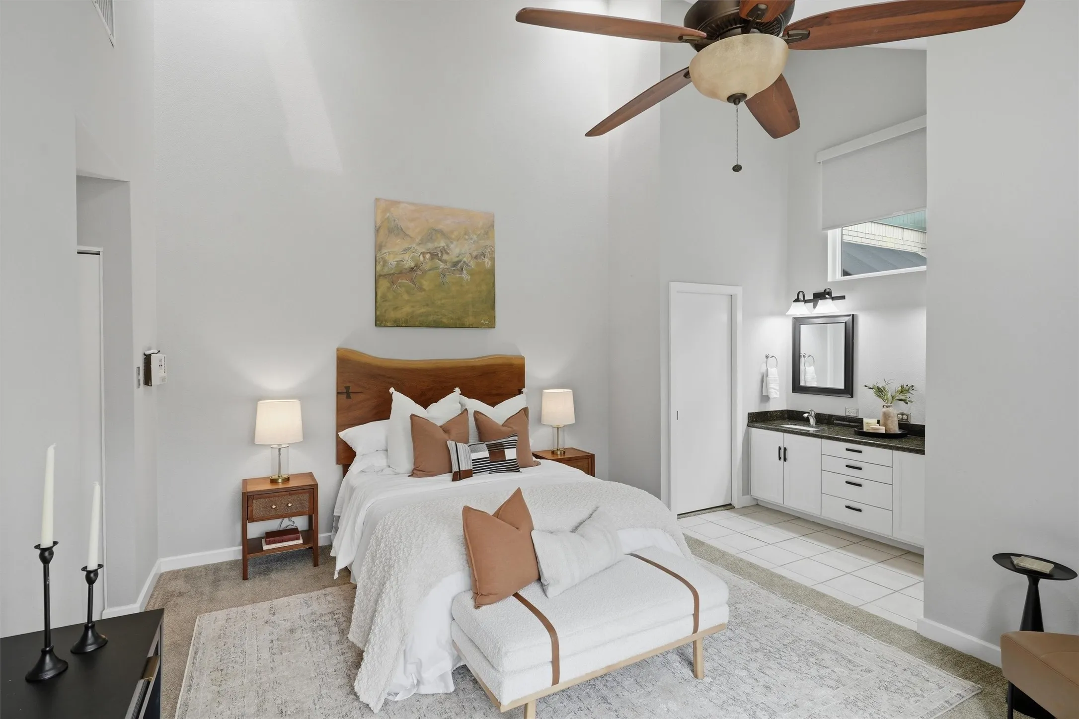 With soaring ceilings, this primary bedroom view highlights a perfectly proportioned sleeping area that transitions smoothly into vanity area.