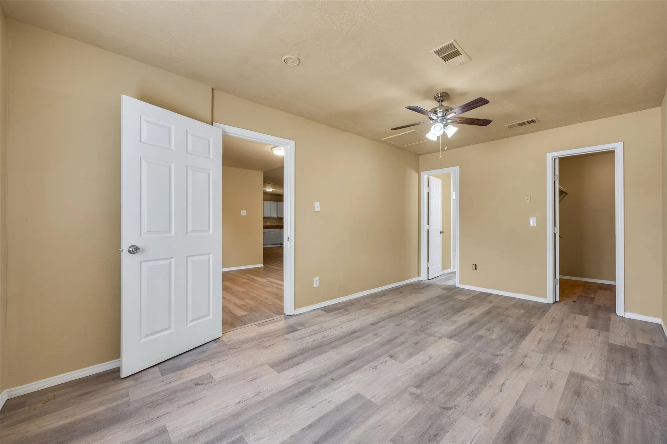 Recessed lighting, ceiling fan with light fixture, wood-finish flooring, multiple doorways, neutral wall paint