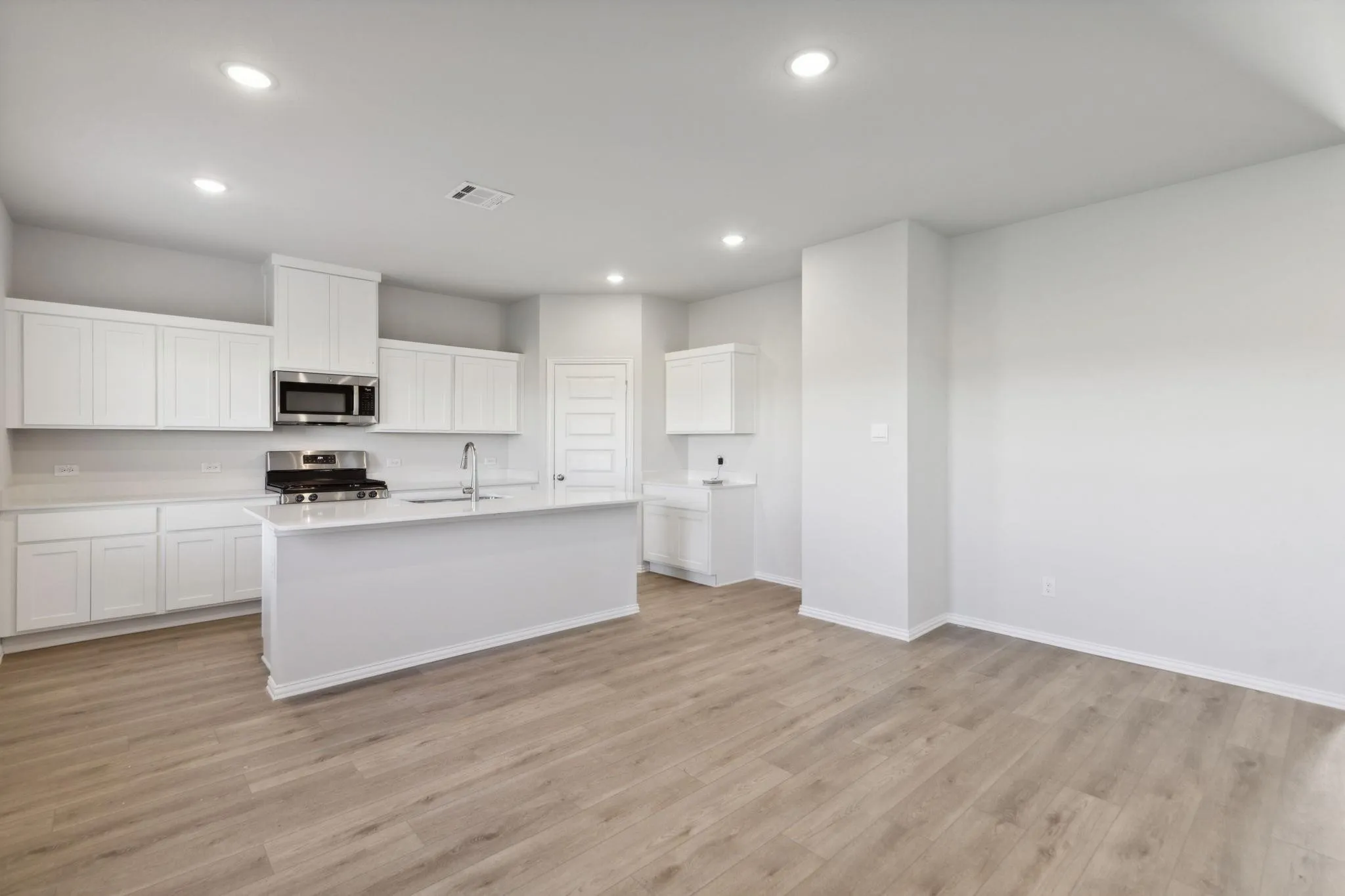 Kitchen with appliances with stainless steel finishes, baseboards, recessed lighting, light wood-style floors, and light countertops