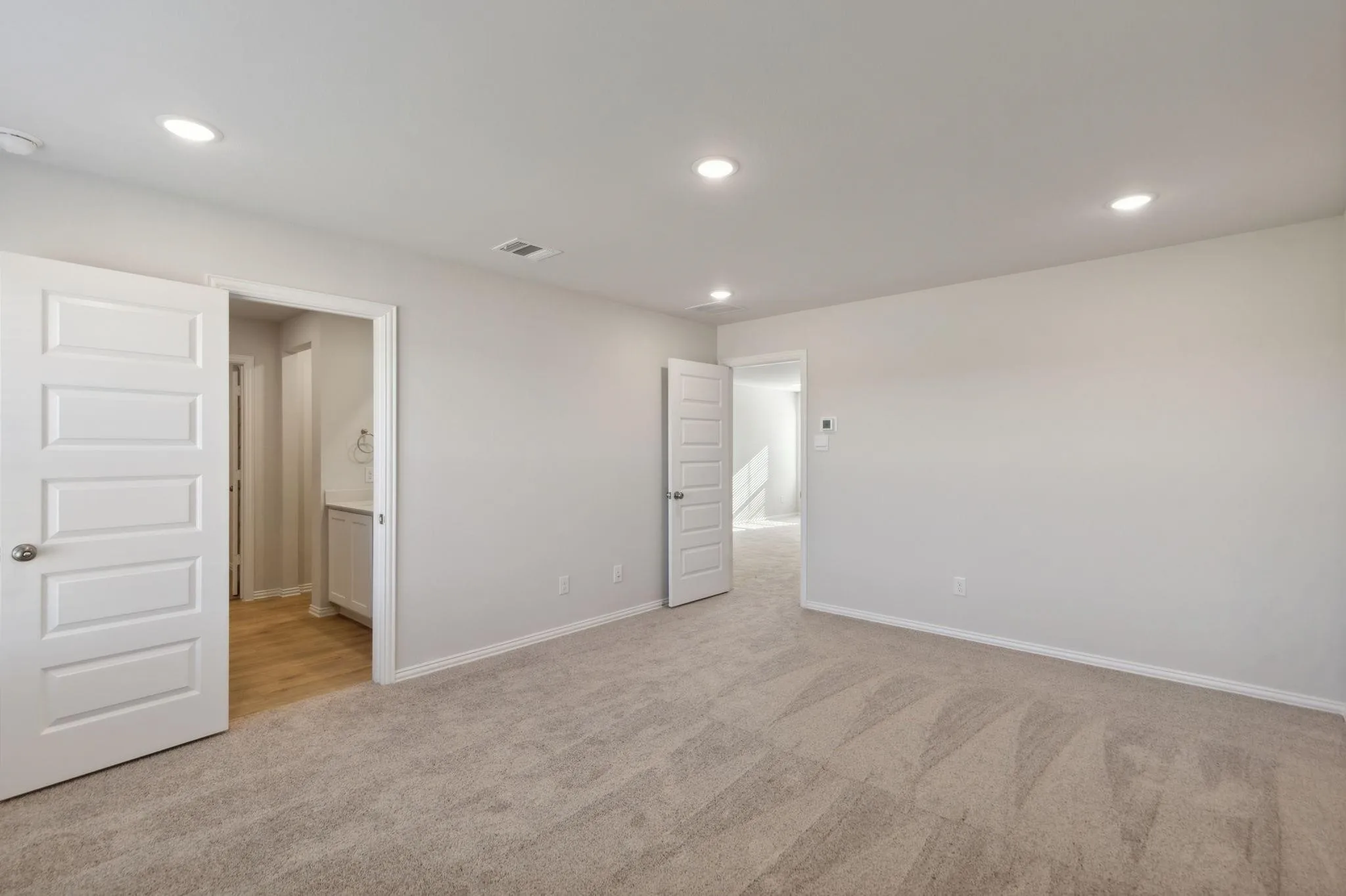 Unfurnished bedroom featuring carpet flooring, baseboards, recessed lighting, and connected bathroom