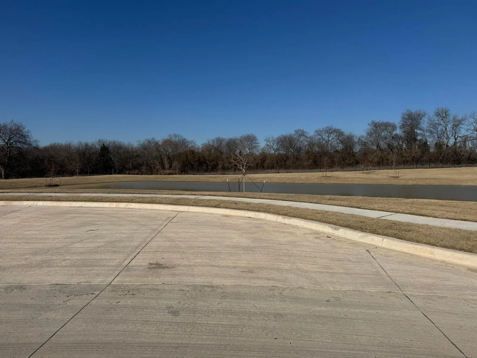 View of concrete road featuring sidewalks, curbs, and view of scattered trees
