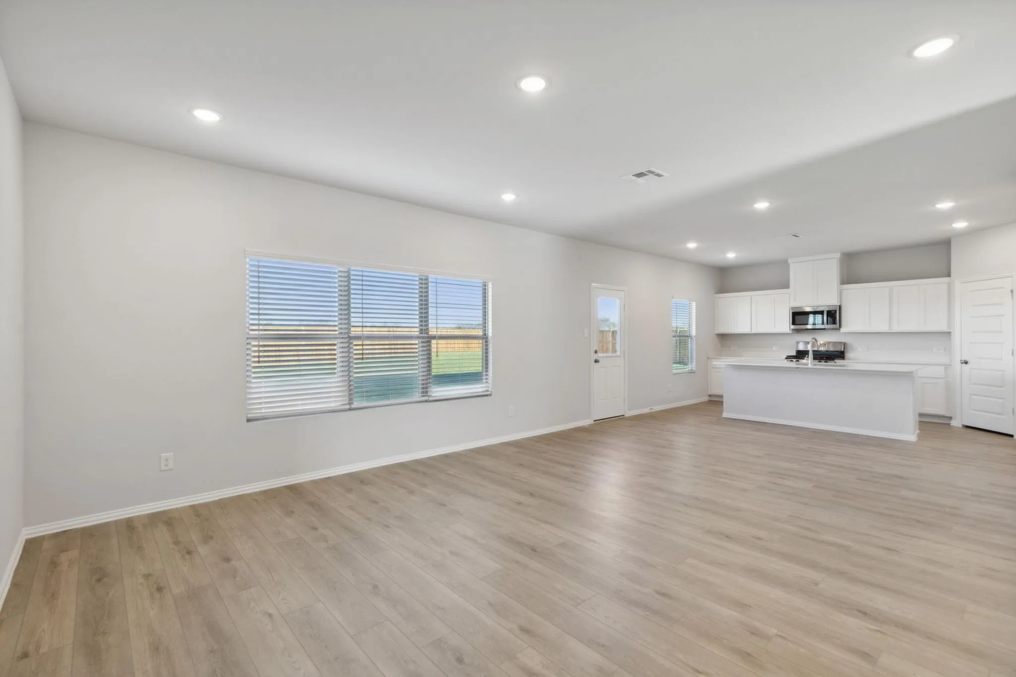 Unfurnished living room with light wood finished floors, recessed lighting, baseboards, and a sink
