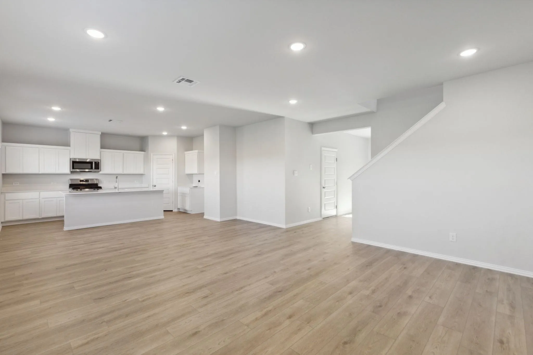 Unfurnished living room featuring recessed lighting, a sink, light wood-type flooring, and baseboards