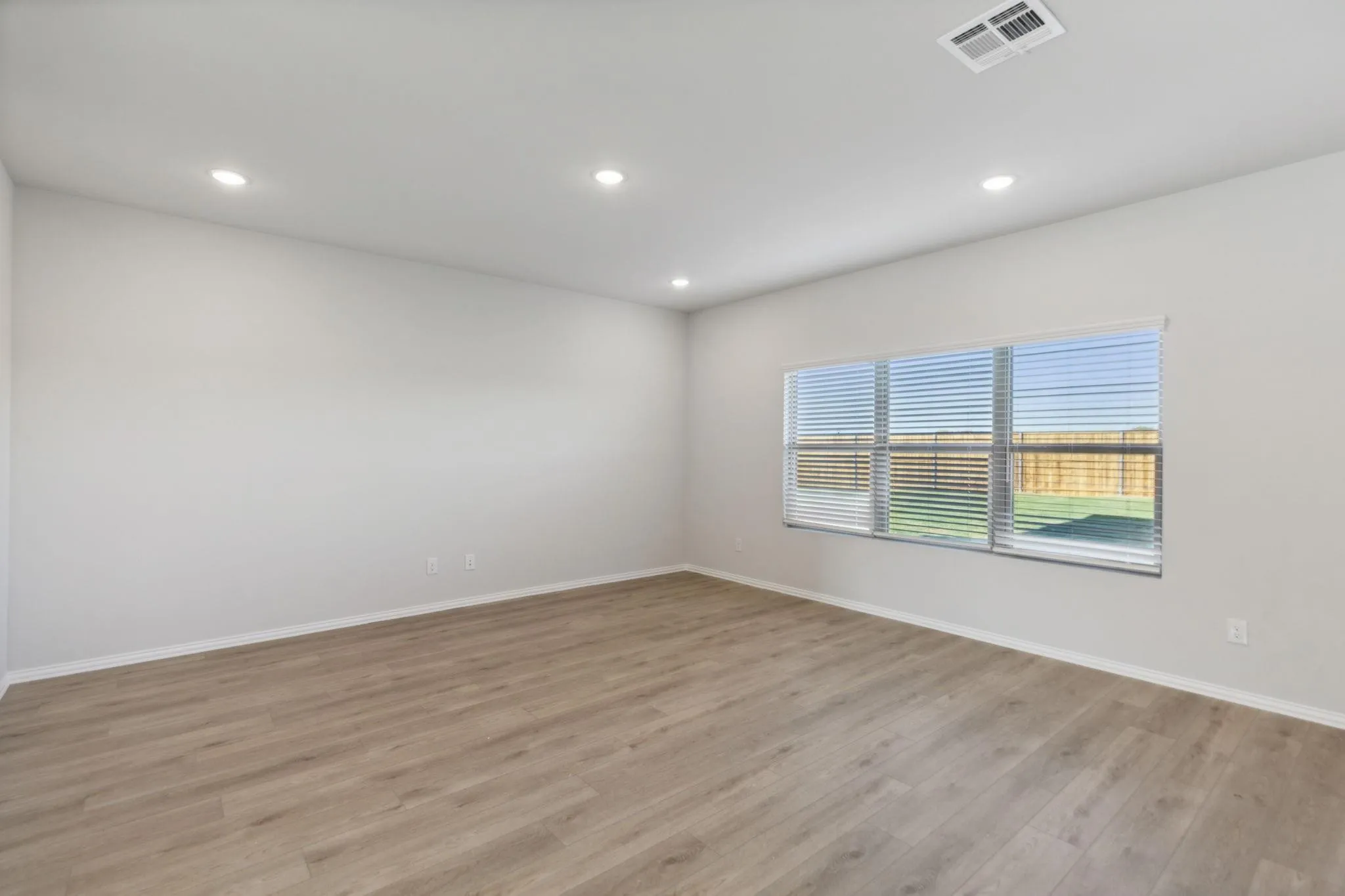 Empty room featuring light wood finished floors, recessed lighting, and baseboards