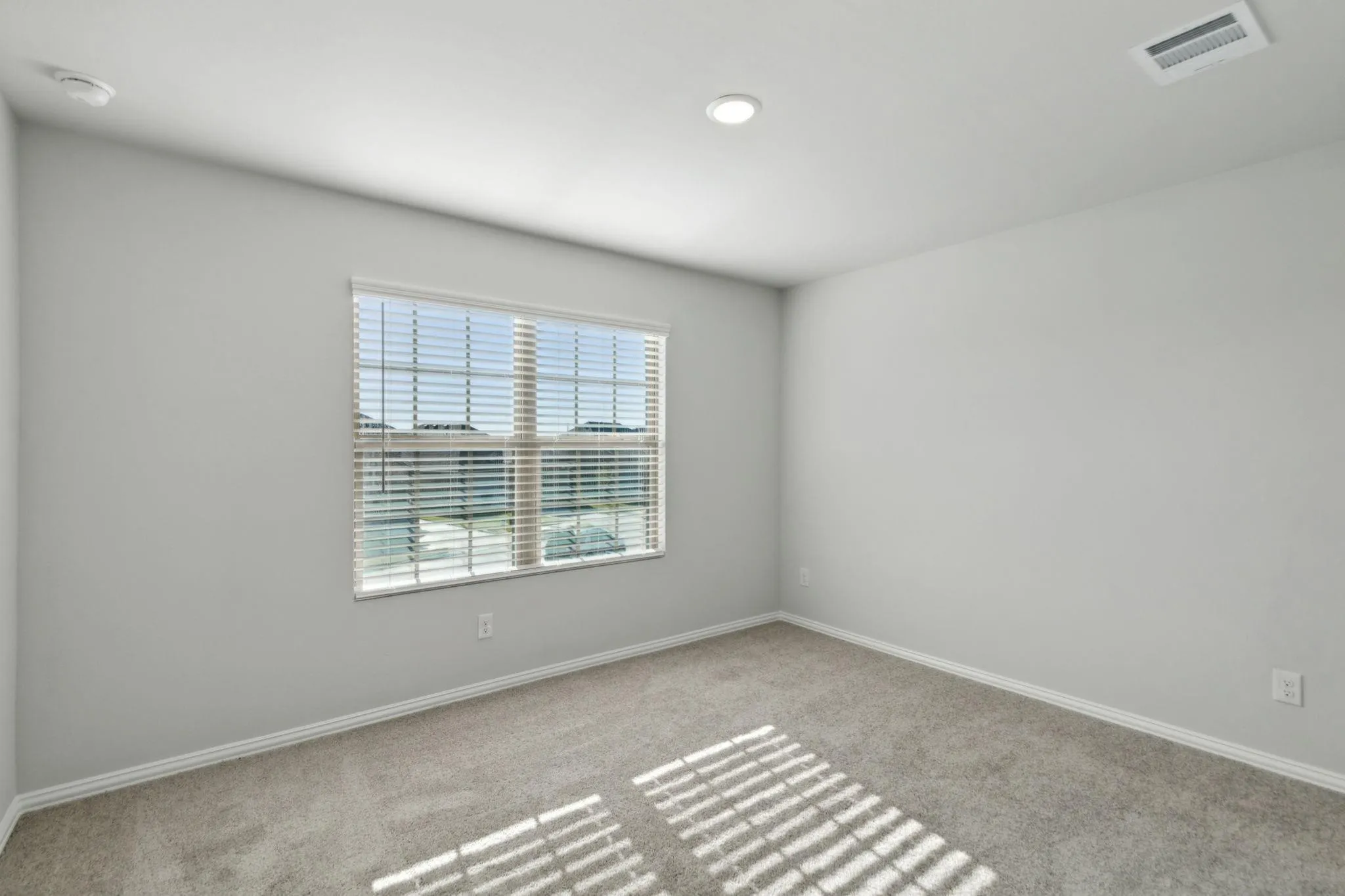 Spare room featuring carpet, baseboards, and a smoke detector