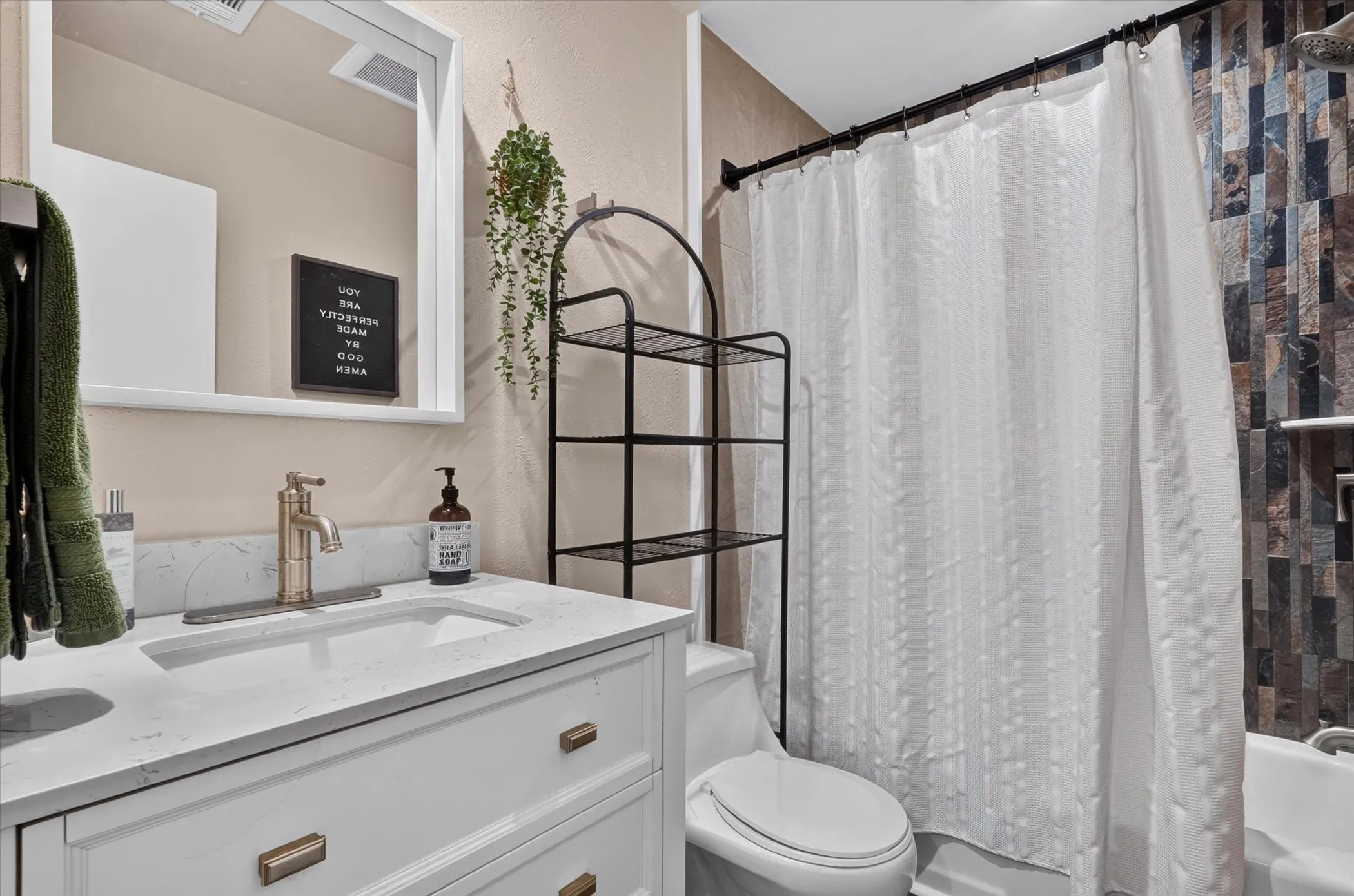 White vanity with integrated sink, brass-tone fixtures, and a framed wall mirror