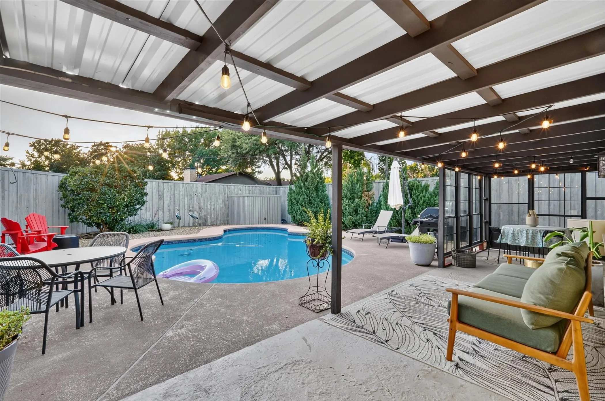 Outdoor living space with a covered patio, string lighting, and a built-in swimming pool