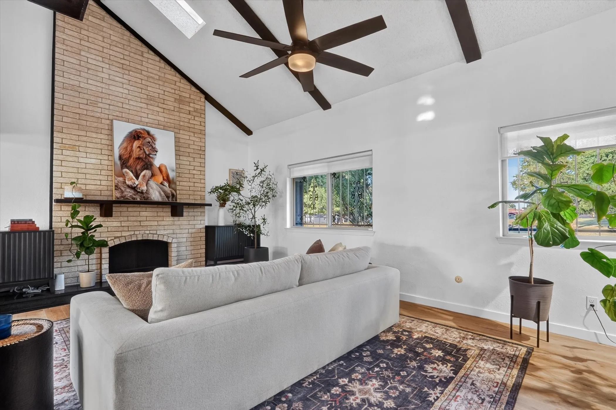 Vaulted ceiling with exposed beams, skylight, and ceiling fan