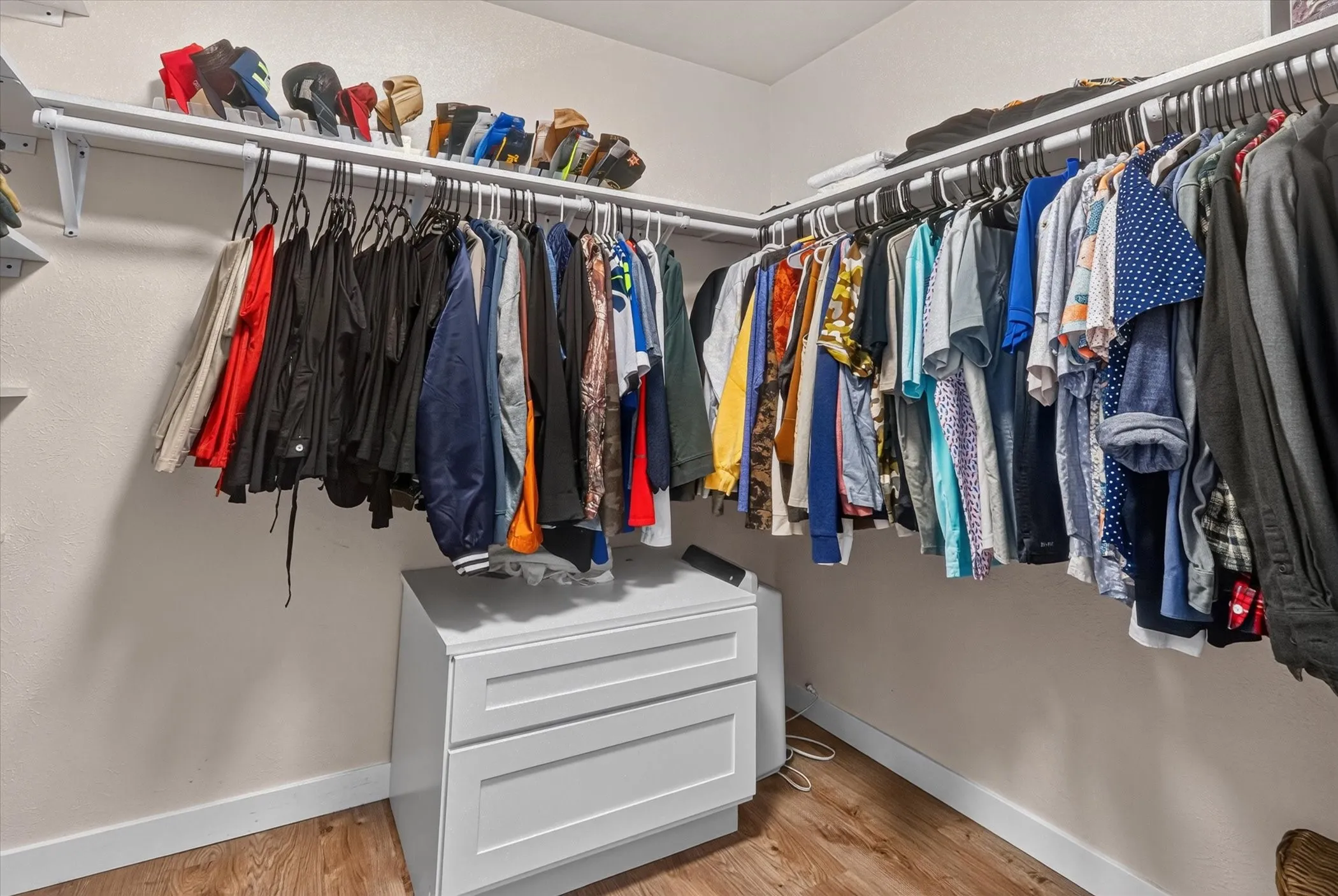 Built-in white shelving system with hanging rods, wood-finish flooring, and light-toned walls
