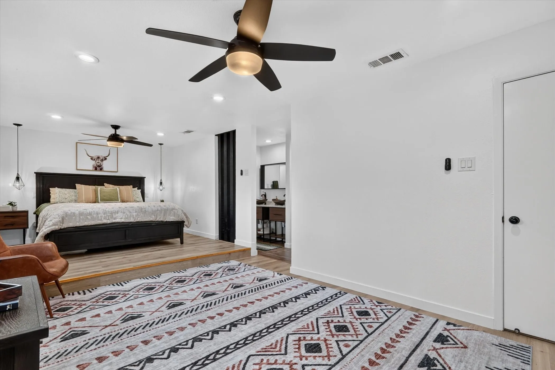 Elevated sleeping area with wood-finish flooring, recessed lighting, and a ceiling fan